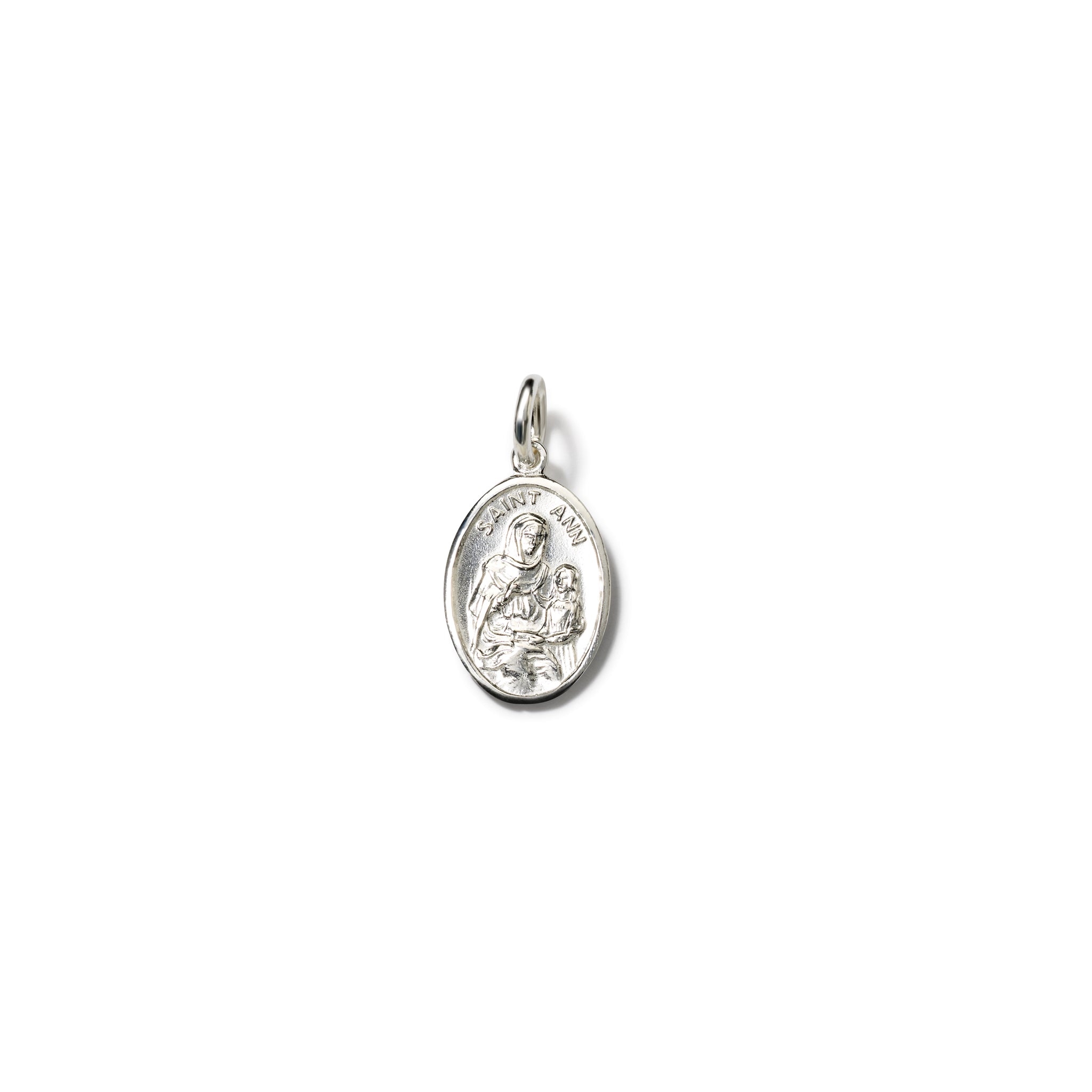Handcrafted oval sterling silver pendant with an engraving of Saint Anne cradling a child and 'Saint Anne' inscribed above. Includes a top loop for chain attachment