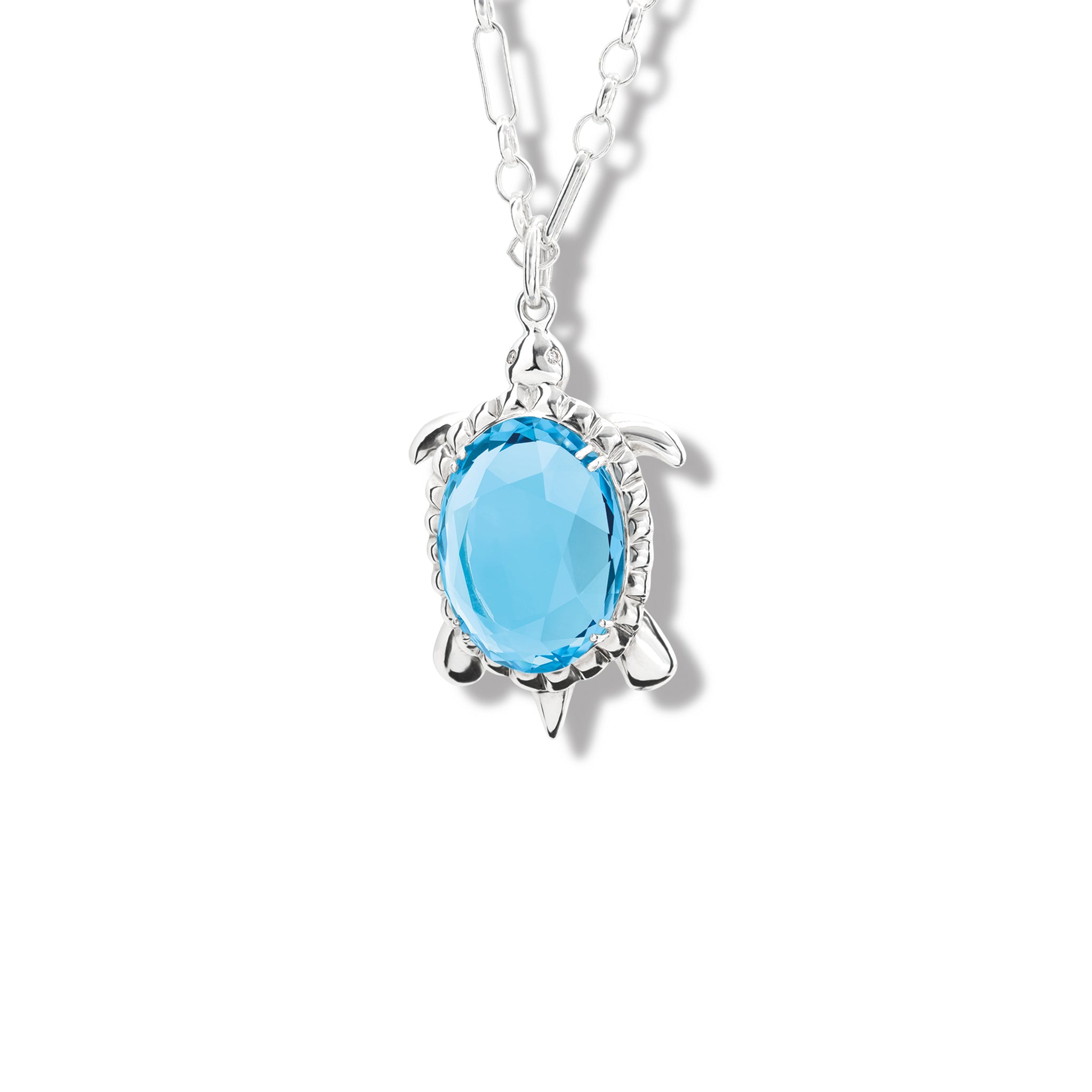 Handcrafted sterling silver tortoise-shaped necklace pendant featuring an oval blue topaz as its shell, surrounded by small diamonds, birthstone of November.