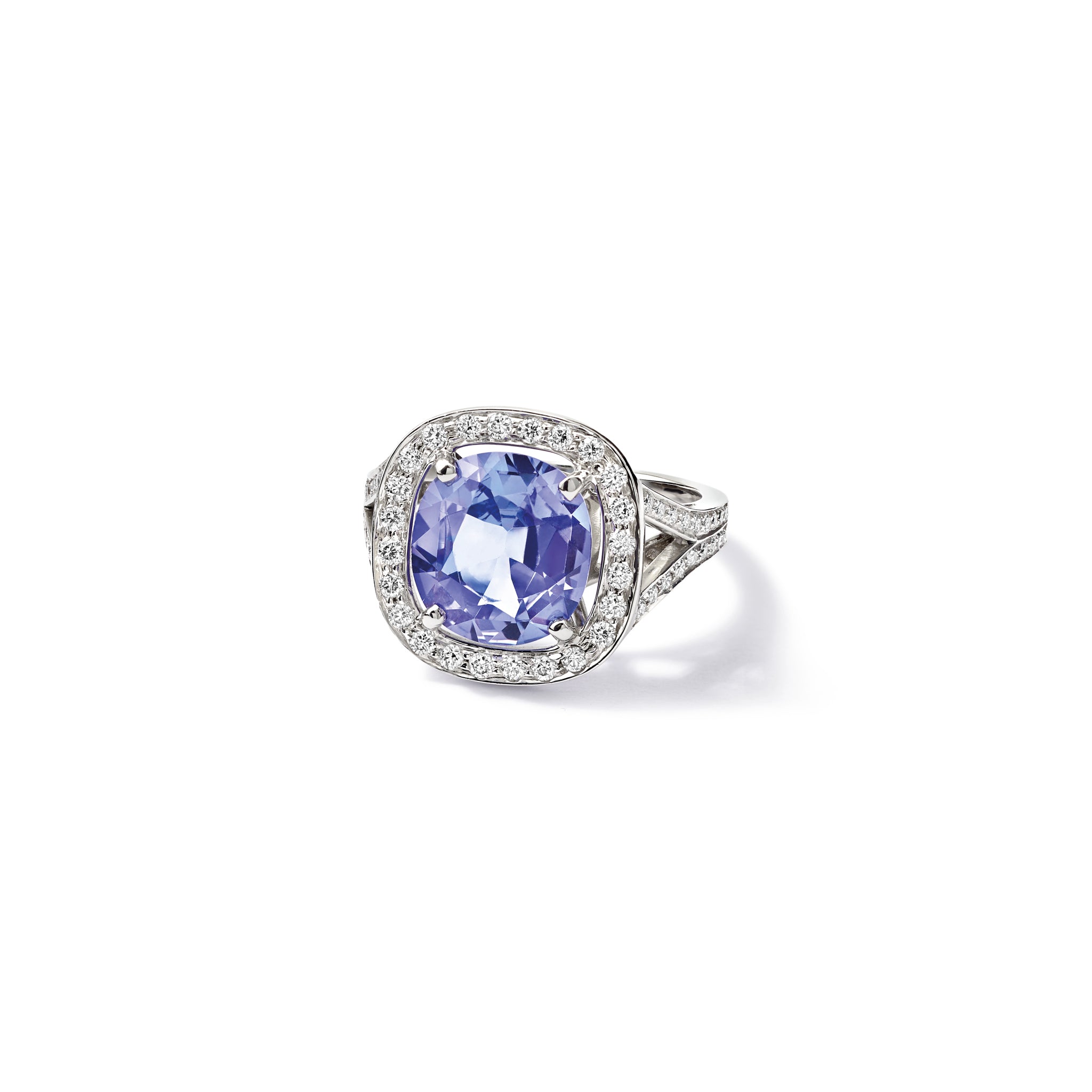 Handcrafted 18ct white gold engagement ring featuring a large, cushion-cut dark blue tanzanite surrounded by a halo of small diamonds and smaller diamonds embedded along the band.