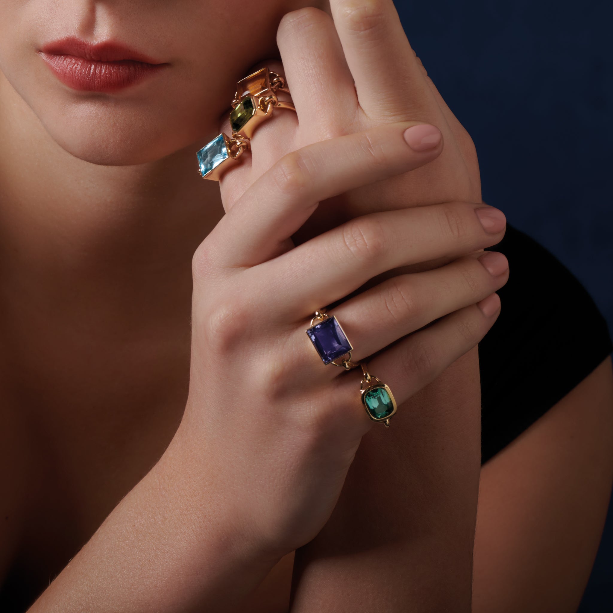 Model wears handcrafted 18ct yellow gold rings featuring different precious gemstones.