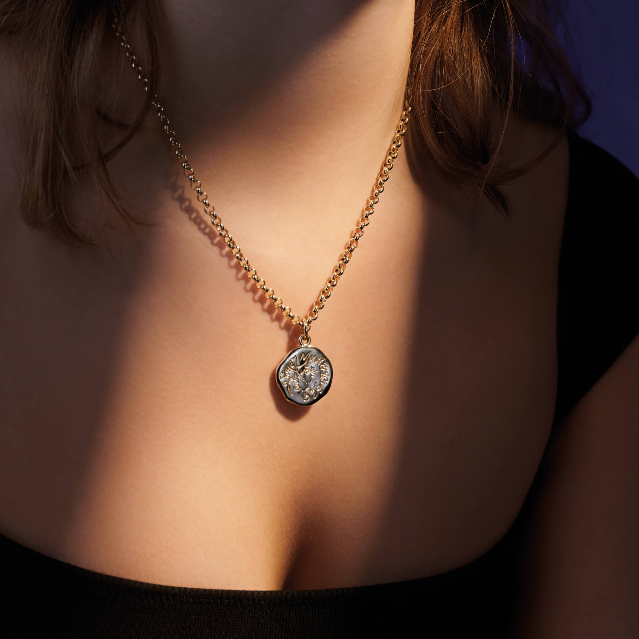 Model wearing a handcrafted round silver pendant necklace engraved with a quote on wonder.