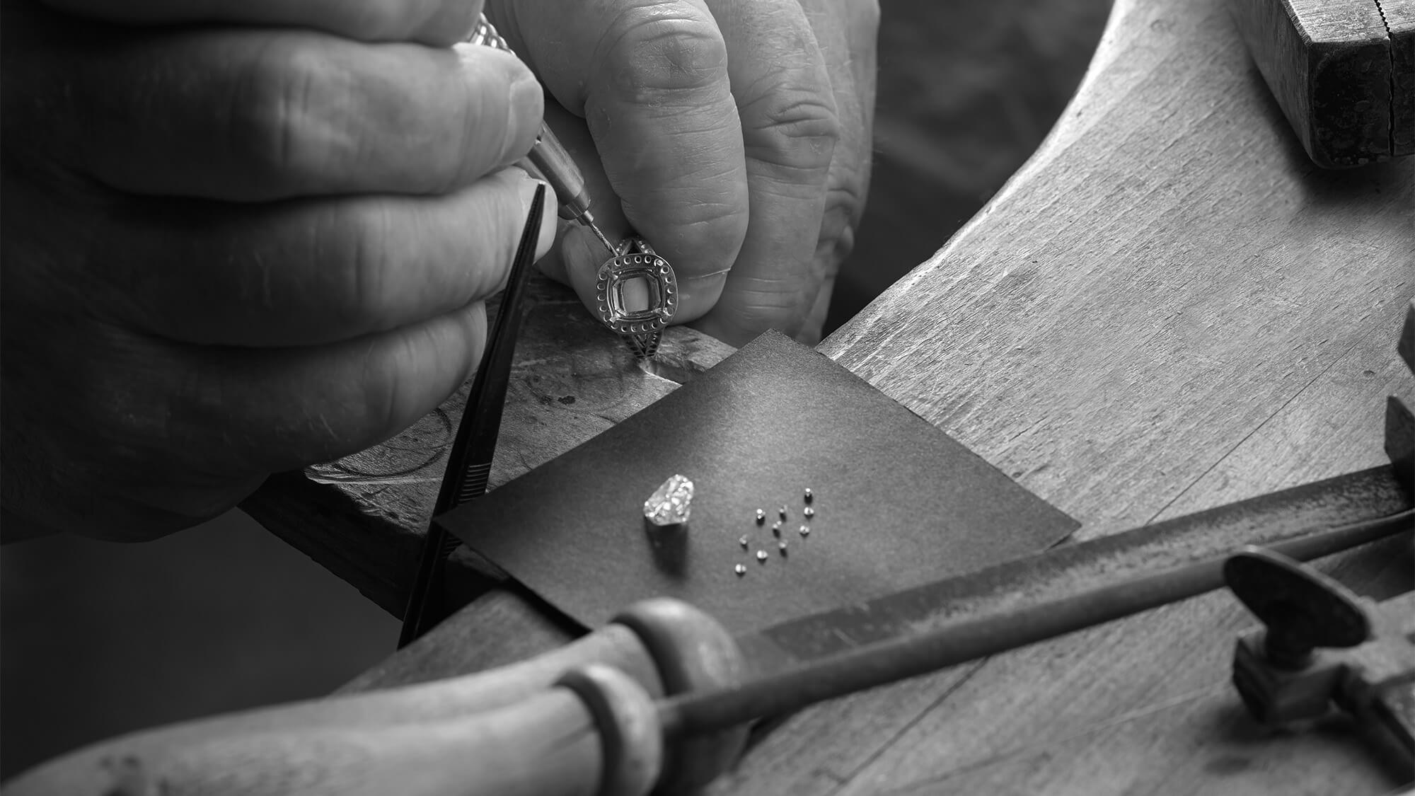 A jeweller setting a handcrafted ring with diamonds in London workshop.