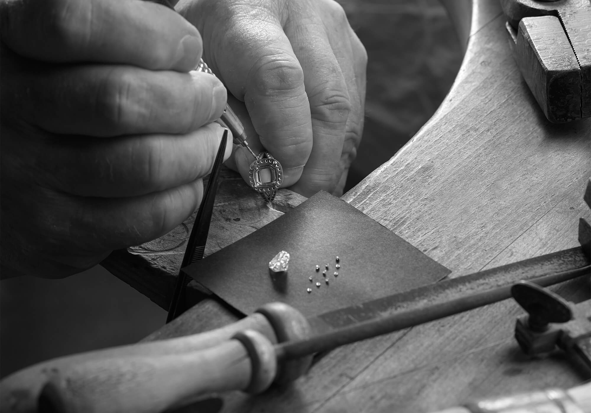 A jeweller setting a handcrafted ring with diamonds in London workshop.