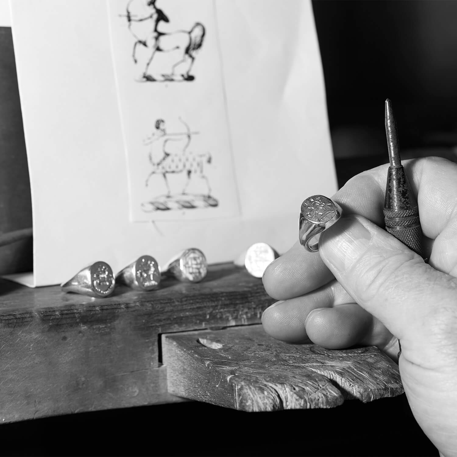 Craftsman hand engraving a signet ring in London workshop.