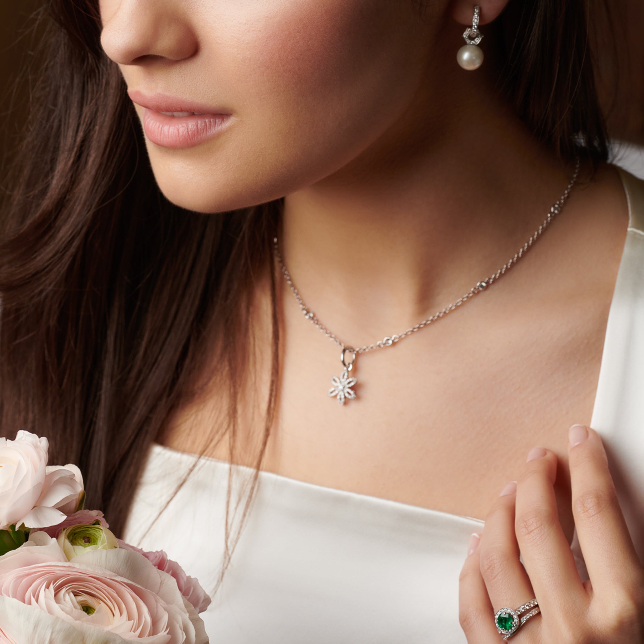 Model wearing a handcrafted 18ct white gold flower necklace pendant with diamond pav� and central diamond, birthstone of April.