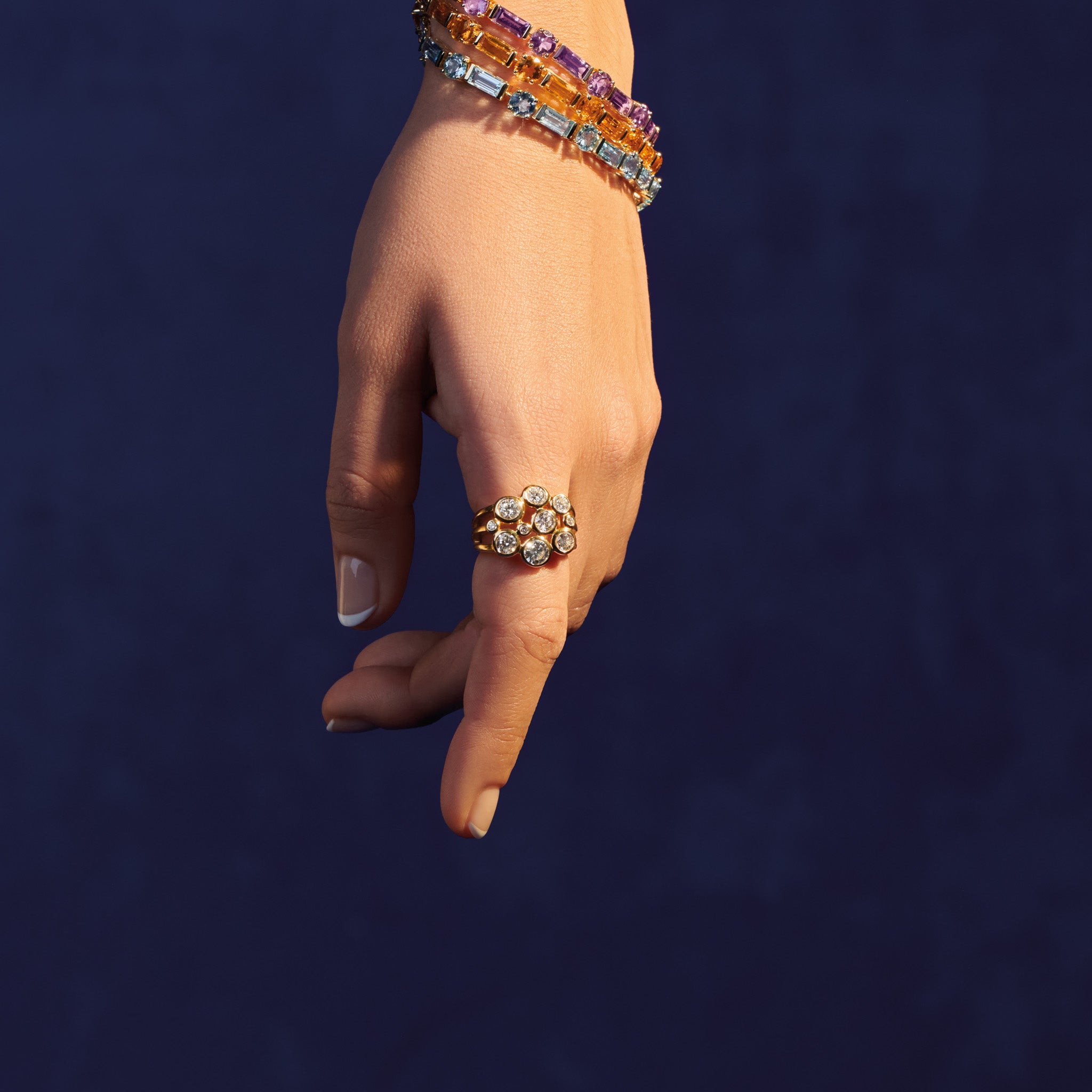 Model wearing a handcrafted 18ct yellow gold ring featuring different sized round diamonds.