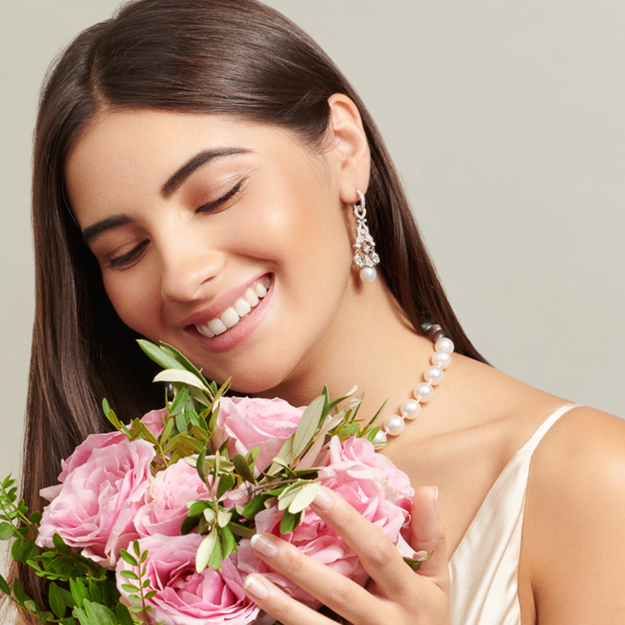 Model wearing handcrafted 18ct white gold earring drops featuring a teardrop shape with diamonds and a pearl at the bottom.