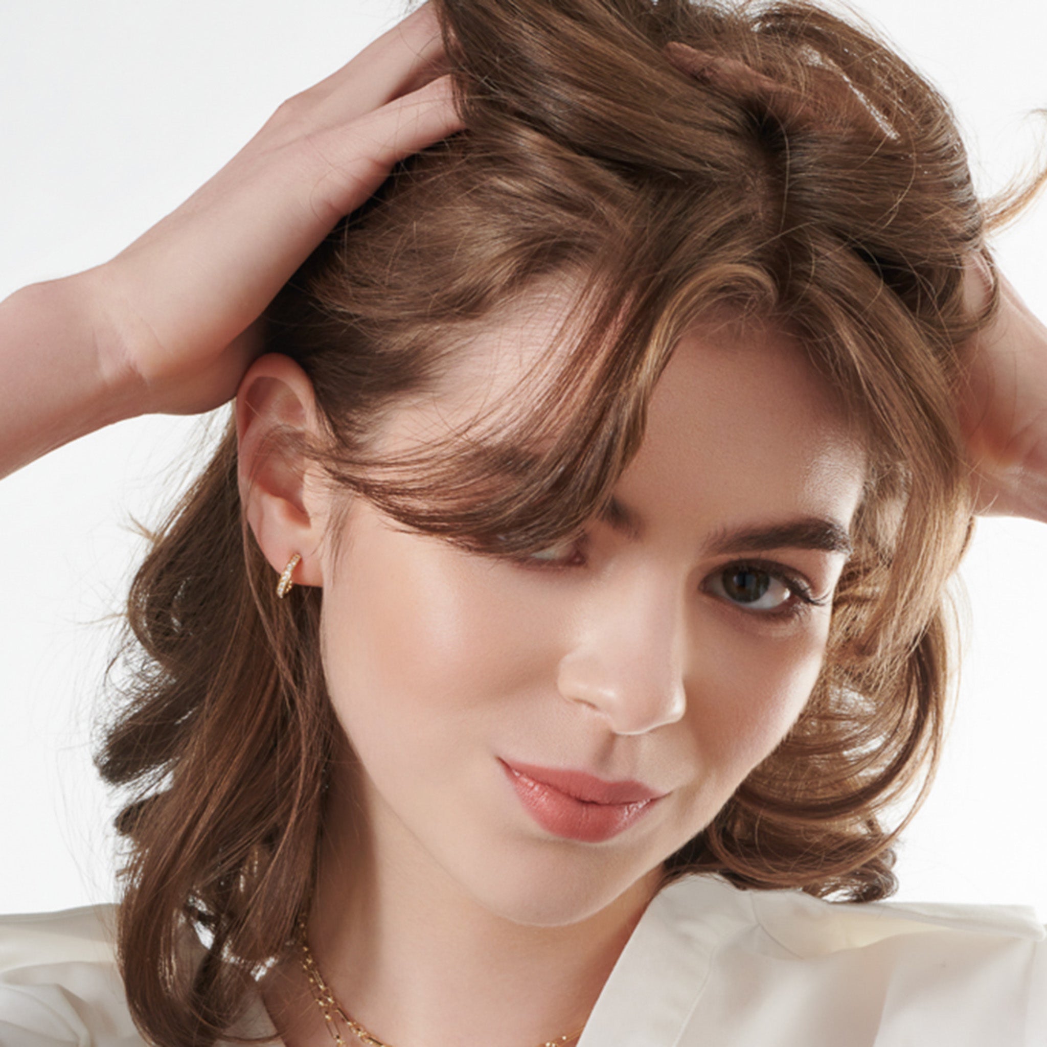 Model wearing a handcrafted sterling silver and white gold hoop earring set.