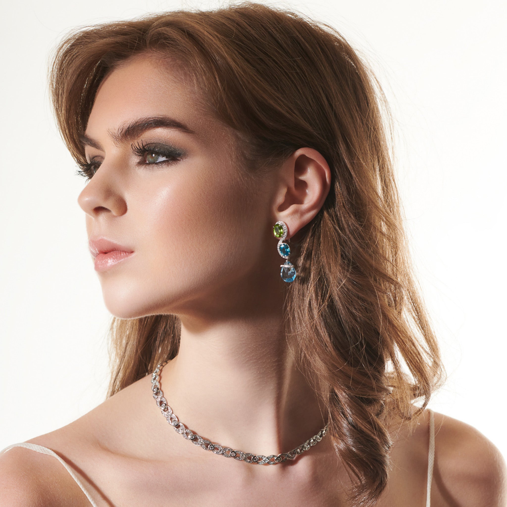 Handcrafted yellow gold earrings featuring an 's' shape linking the aquamarine and pearl.