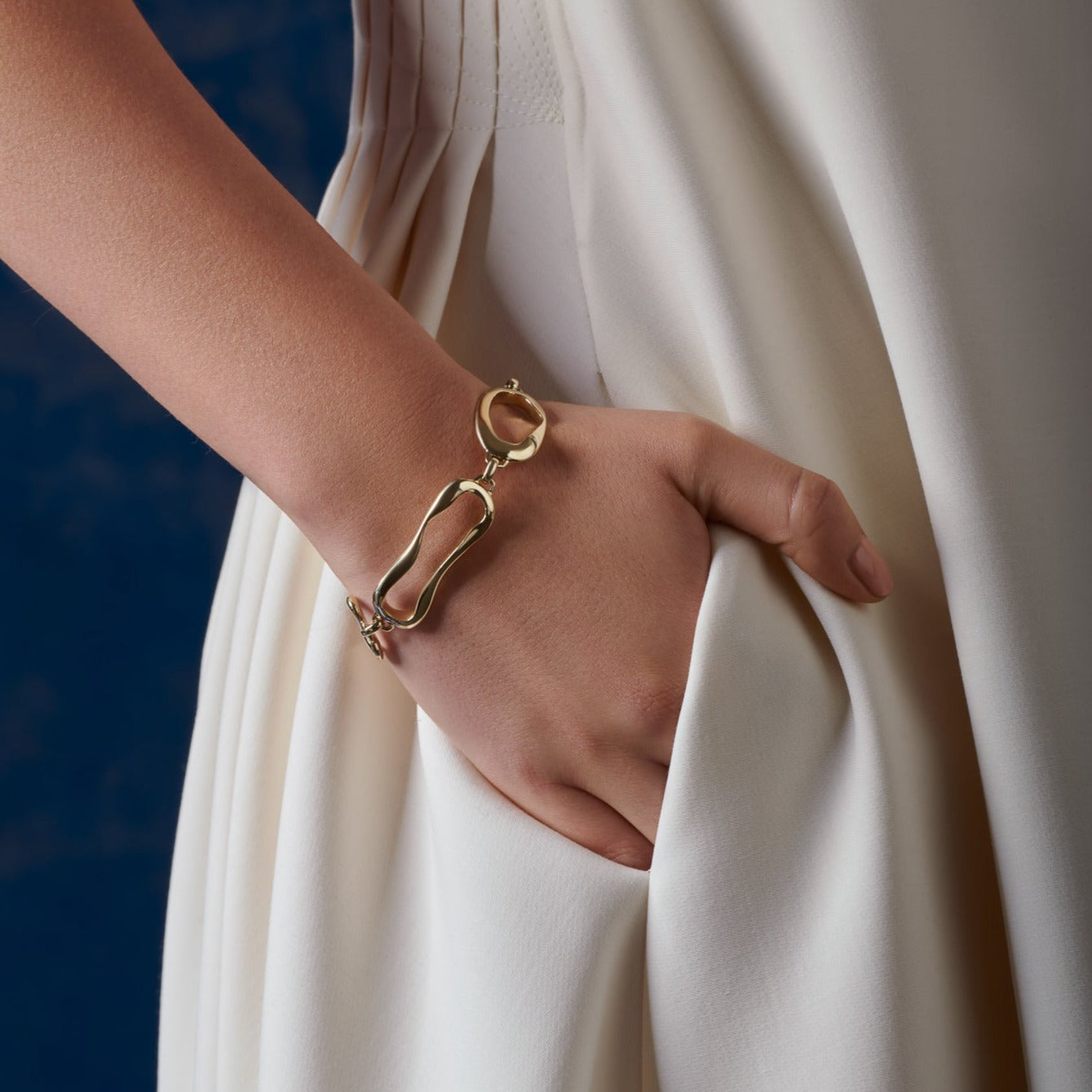 Model wearing a handcrafted yellow gold bracelet featuring the outlines of french pastries: ?clair, canel?, pain au chocolat and croissant.