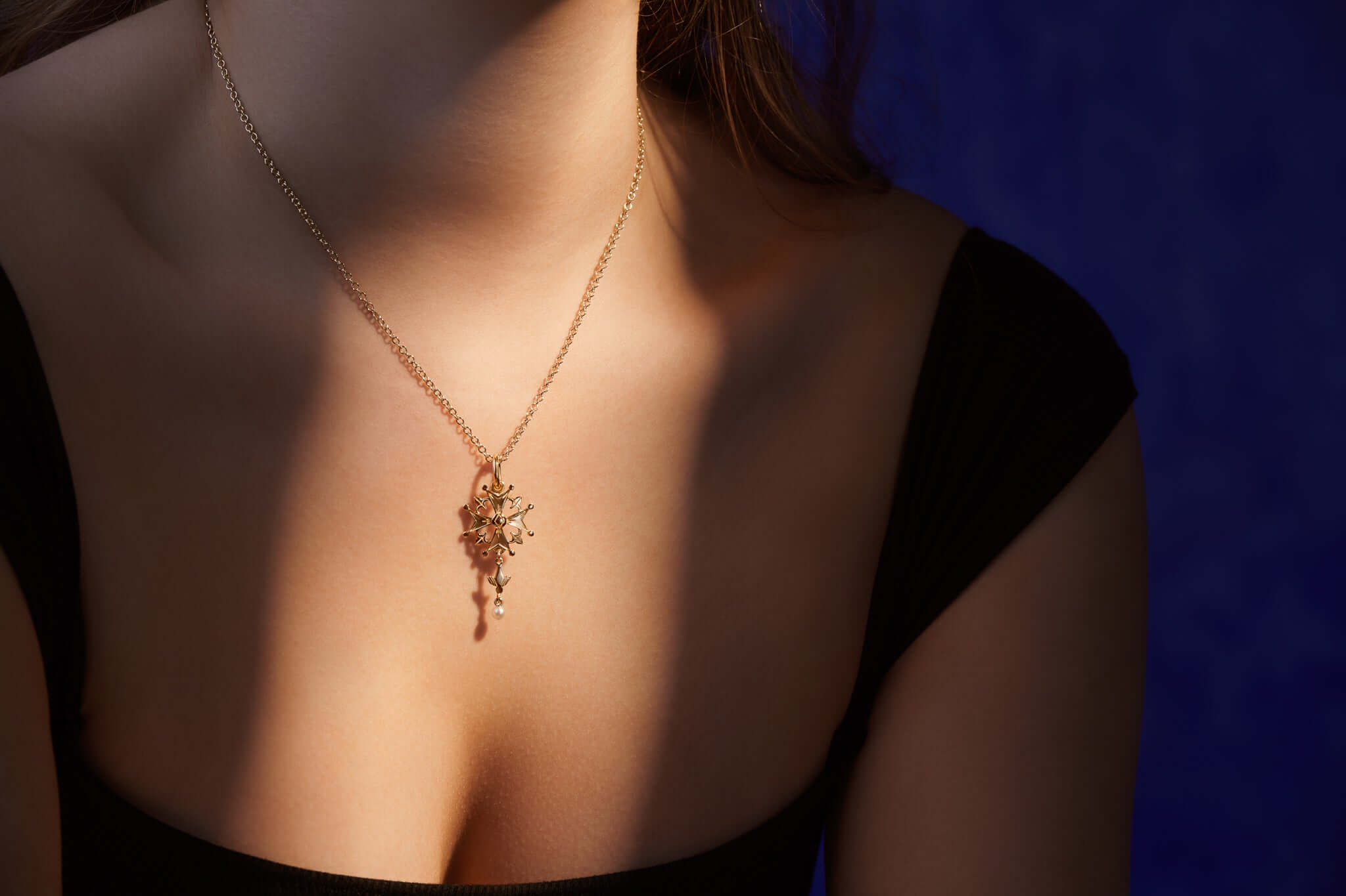 Model wearing a handcrafted yellow gold necklace pendant with a pearl on a delicate chain, showcasing all necklace pendants.