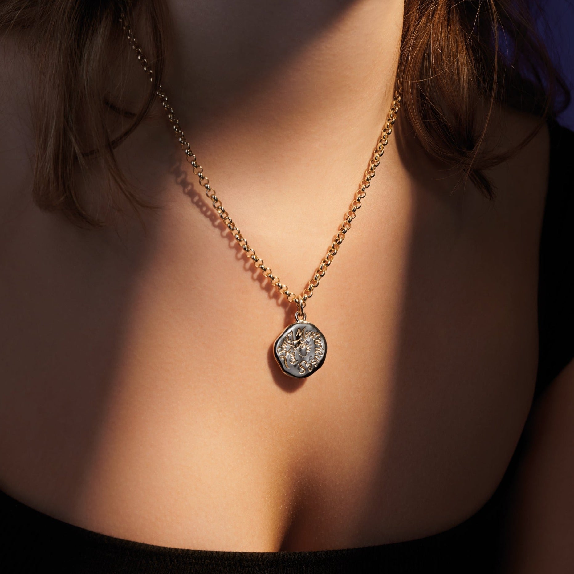 Model wearing a handcrafted round yellow gold necklace pendant engraved with a quote.