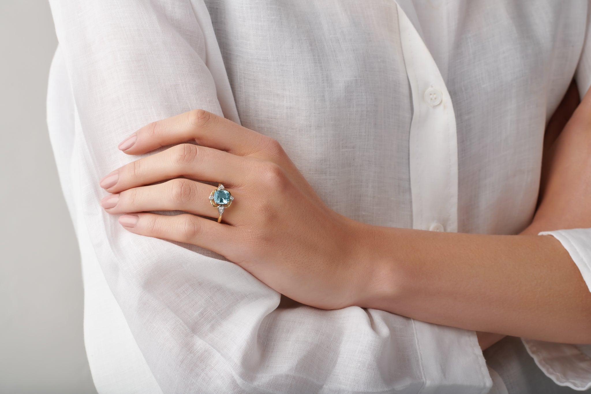 Model wearing a handcrafted yellow gold ring featuring a facetted aquamarine, birthstone of March.