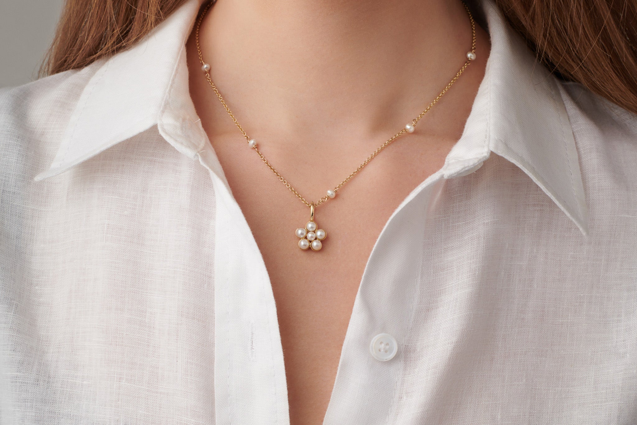 Model wearing a handcrafted yellow gold necklace pendant in the shape of a forget-me-not, perfect for thoughtful anniversary gifting.