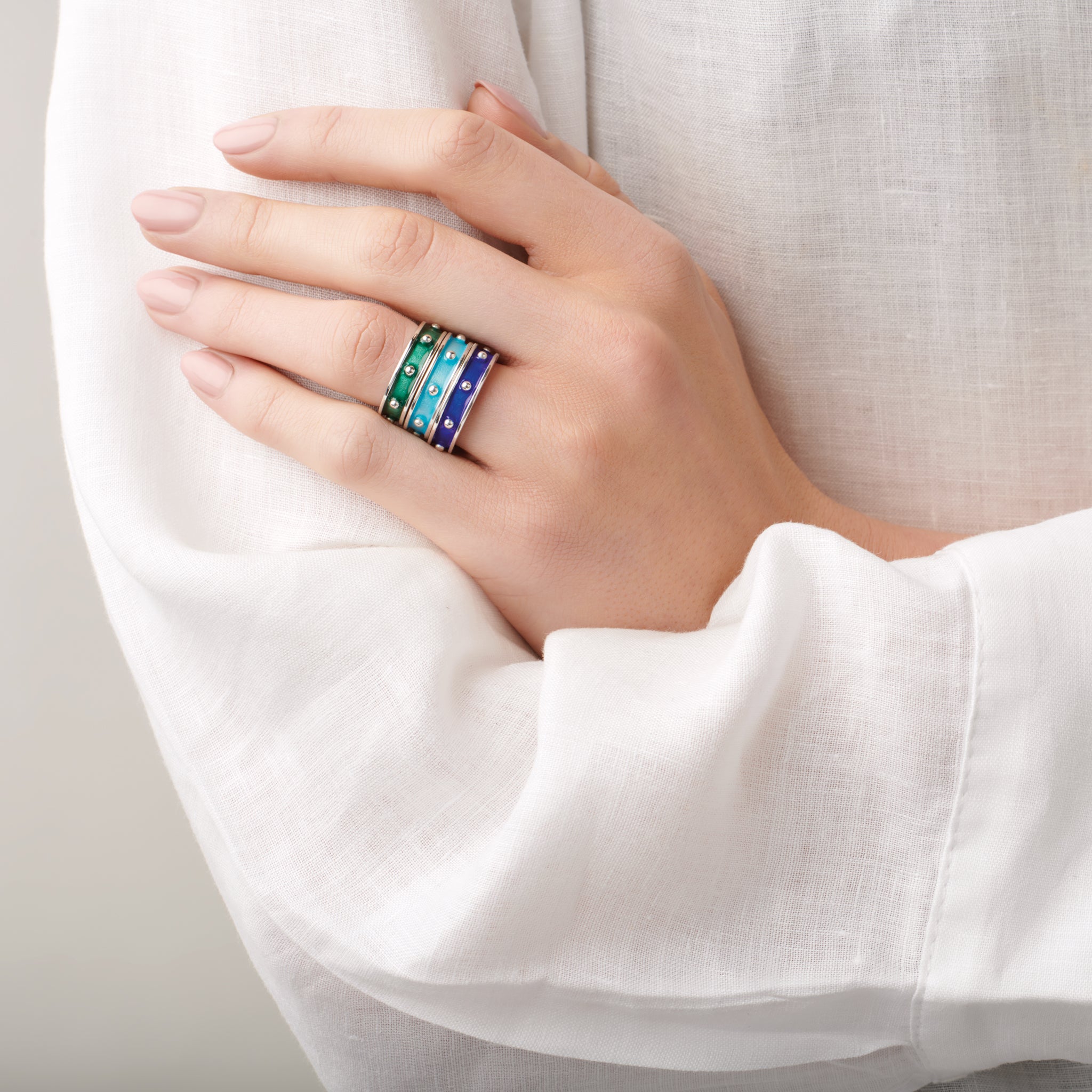 Model wearing handcrafted 18ct yellow gold rings with evenly spaced, protruding round dots with dark blue enamel.