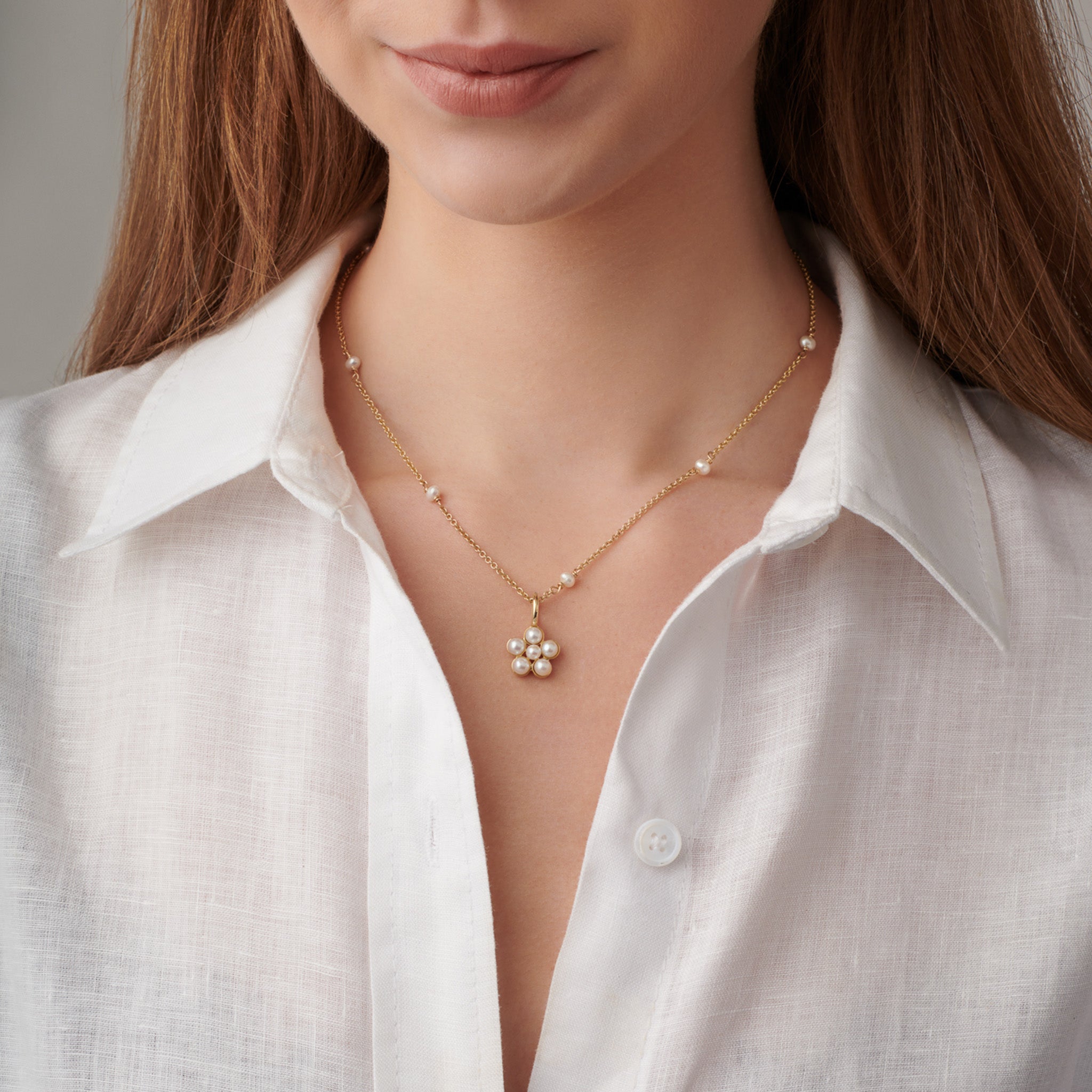 Model wearing a handcrafted flower shaped pearl necklace pendant in precious metal.