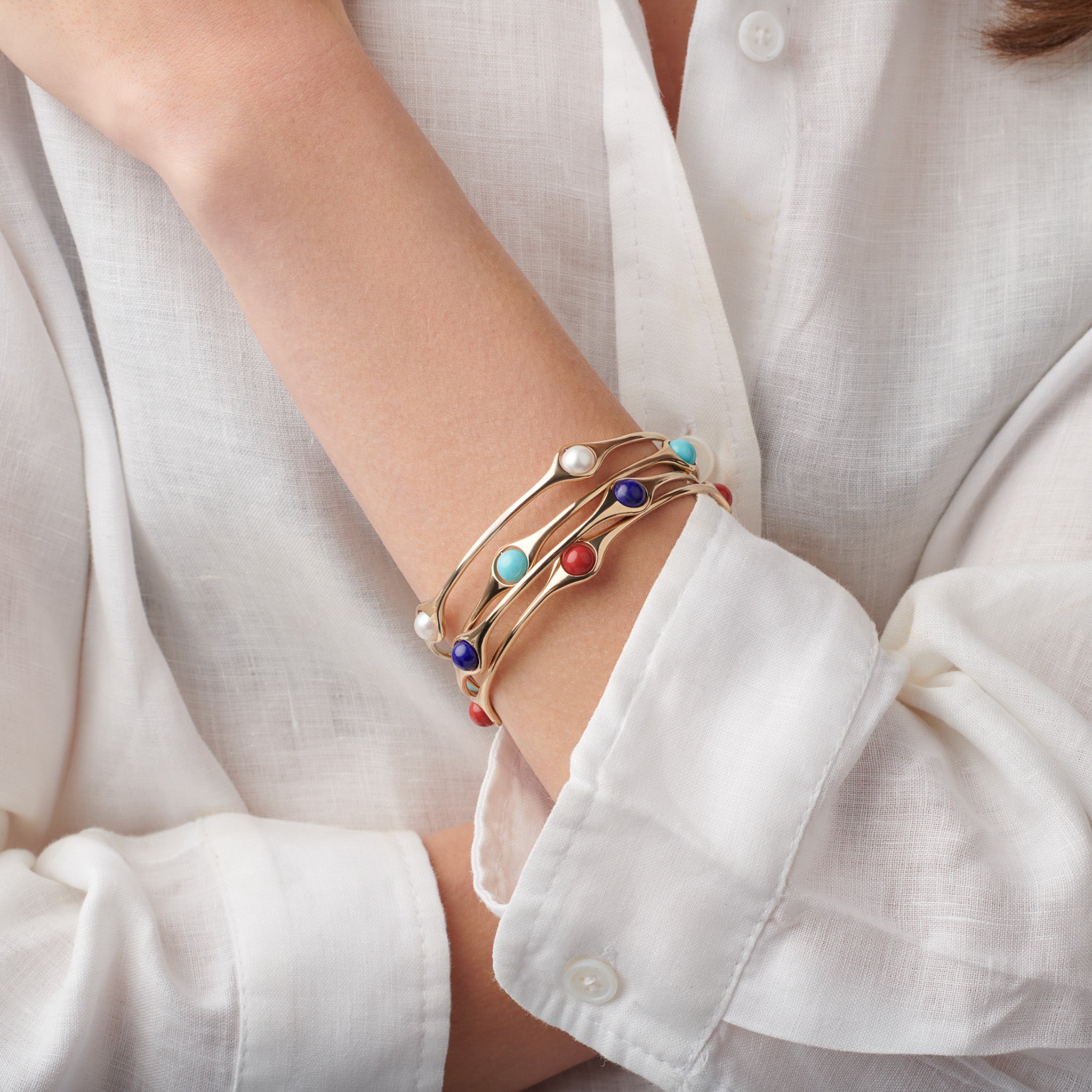 Model wearing three handcrafted yellow gold bangles featuring four beads.