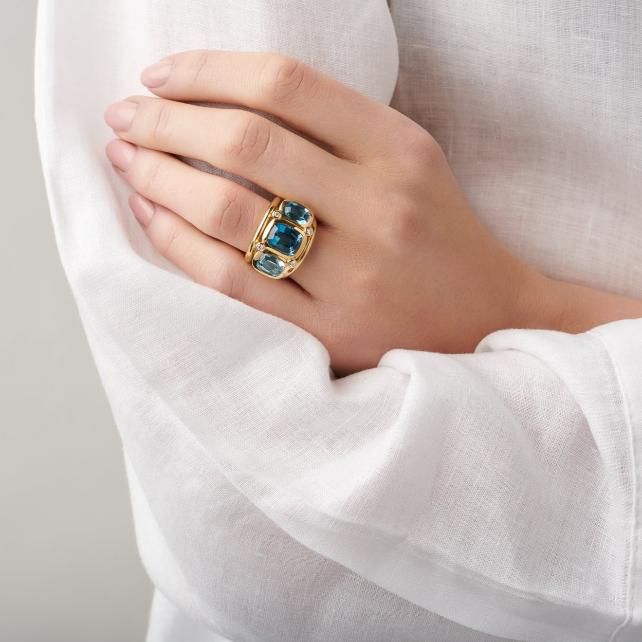Model wearing a handcrafted 18ct white gold ring featuring rectangular shaped blue topaz and diamonds.