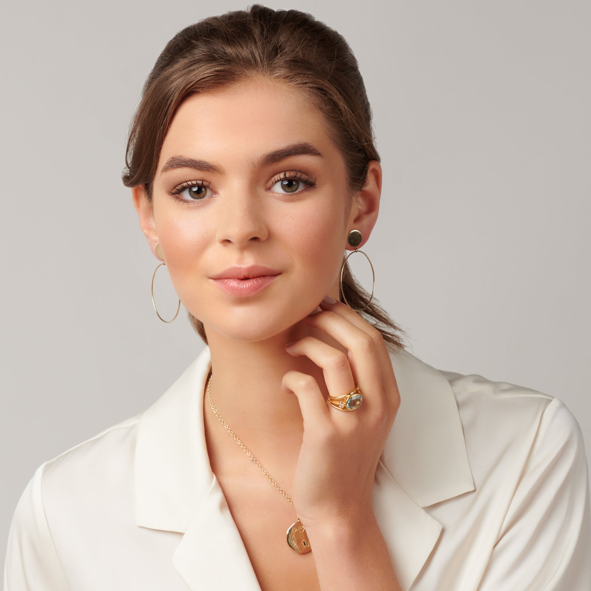 Model wearing a handcrafted ring in precious metal with a central precious stone, flanked by two round diamonds.
