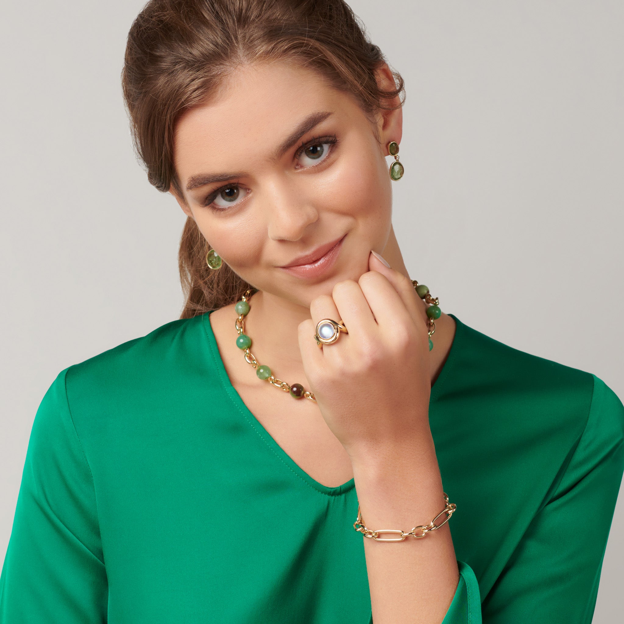 Model wearing a handcrafted ring in precious metal featuring curved shanks with a round large precious stone.