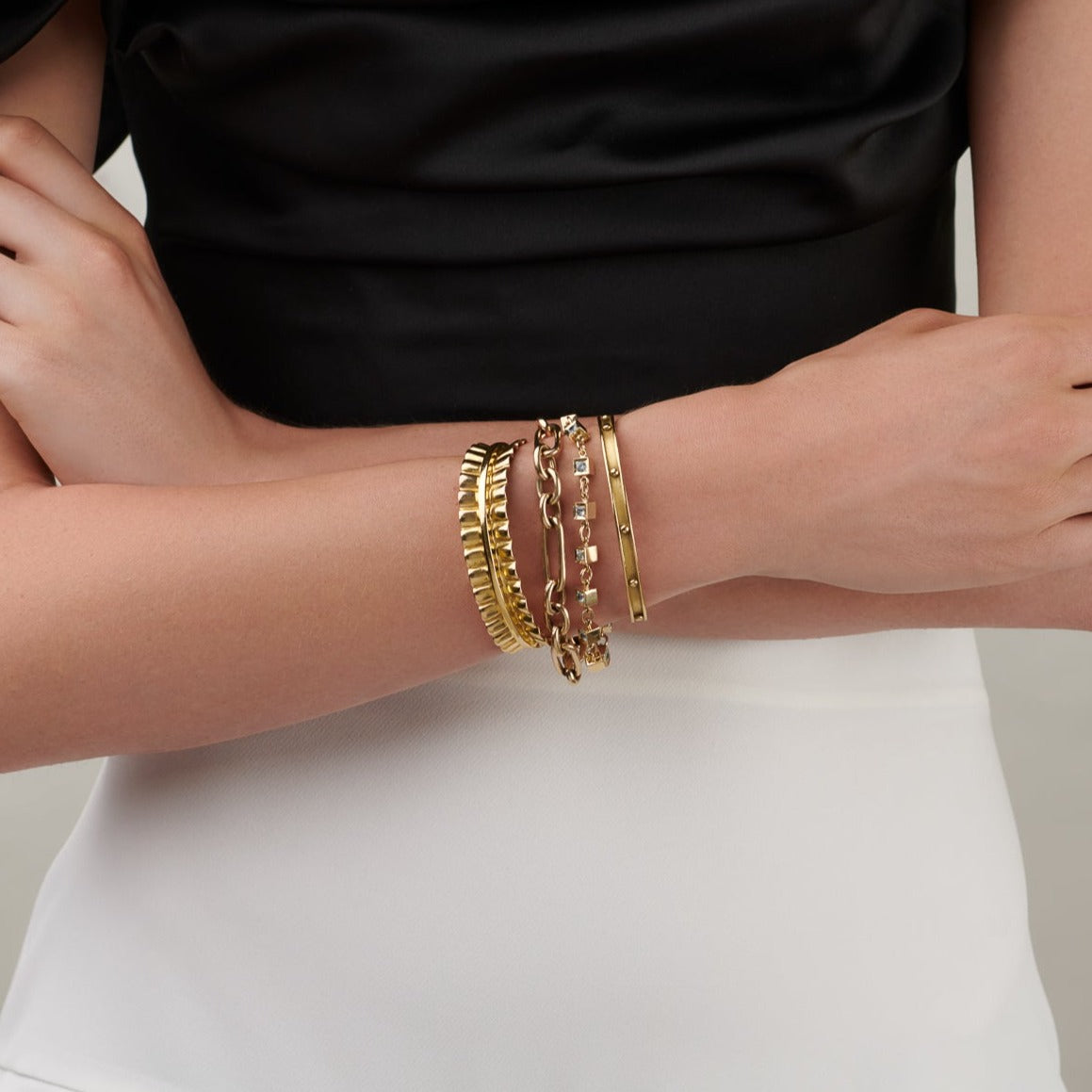 Model wearing a handcrafted yellow gold bracelet cuff with evenly spaced, protruding round dots.