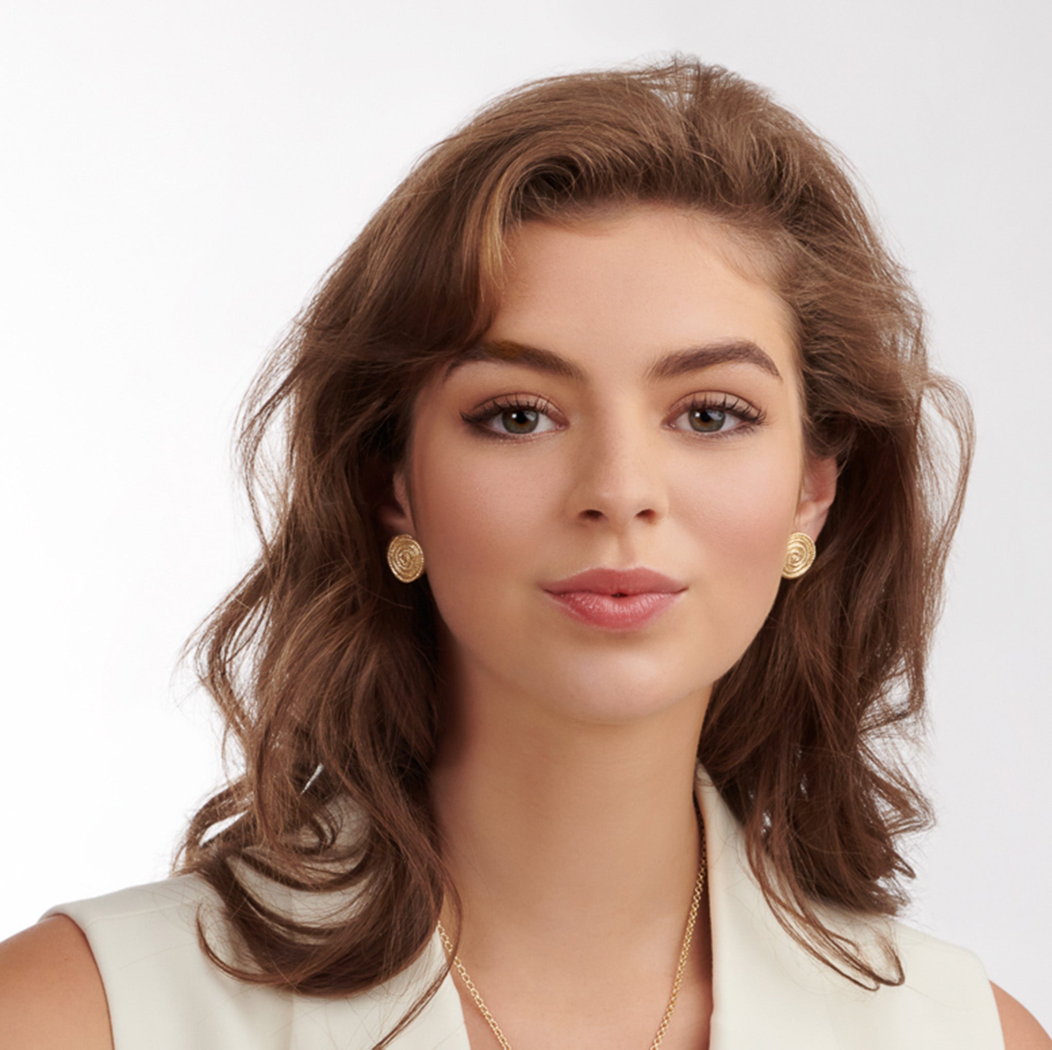 Model wearing a handcrafted yellow gold earring studs with a woven swirl design.