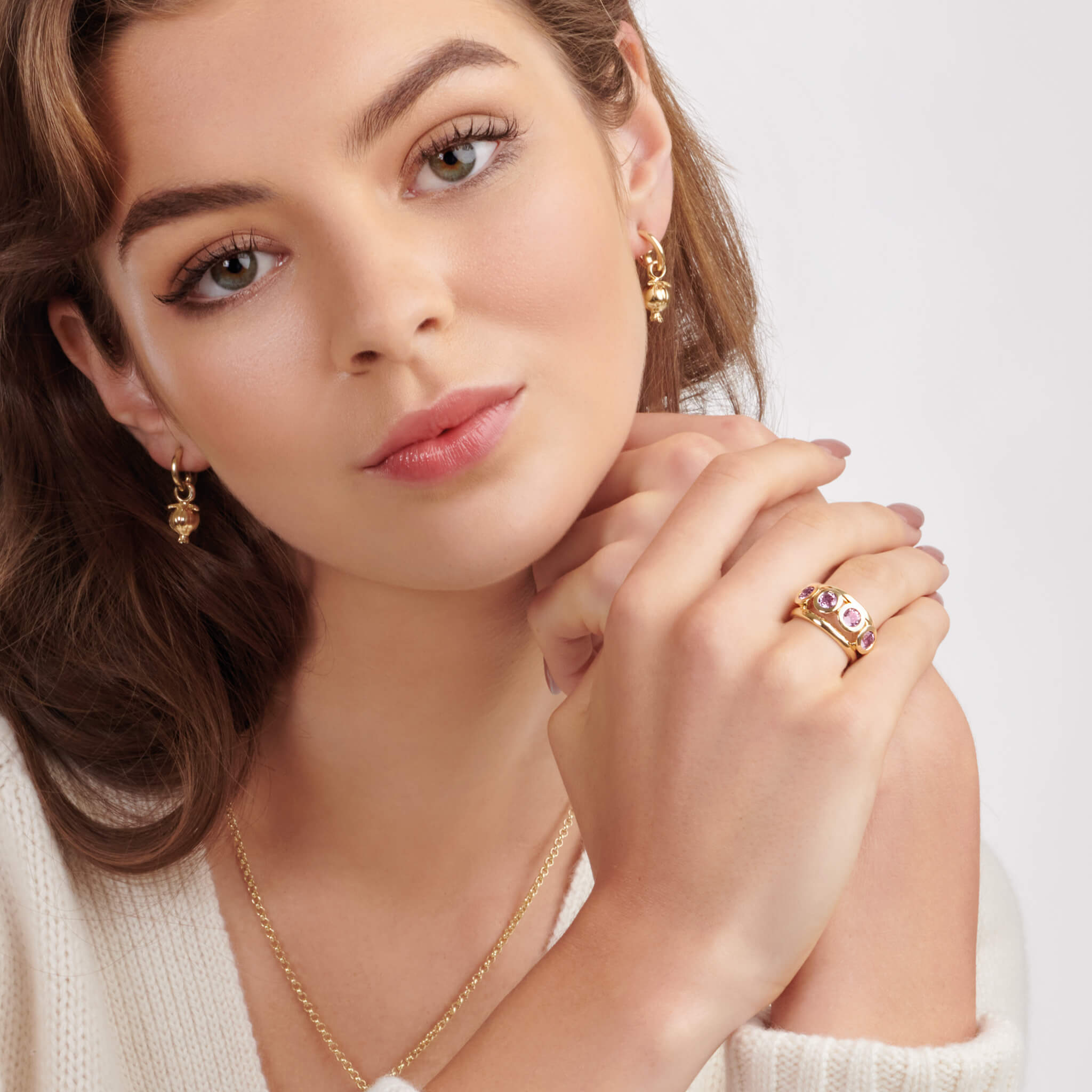 Model wearing a handcrafted yellow gold ring with a bold band and five circular amethyst  gemstones, birthstone of February, in bezel settings.