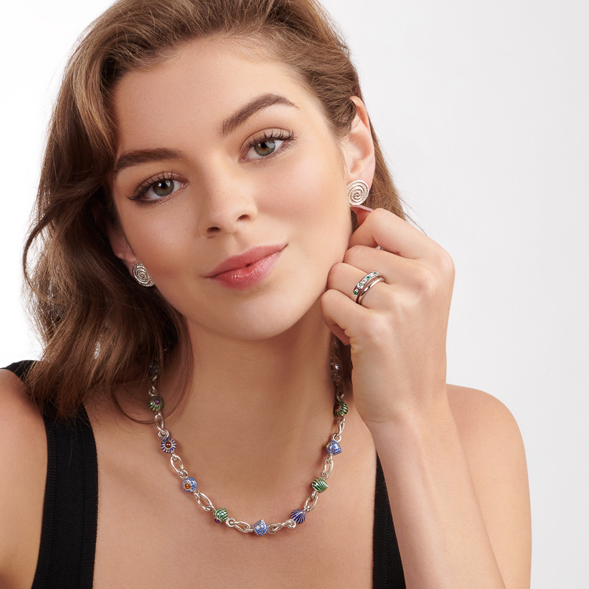 Model wearing a handcrafted 18ct white gold wedding band or eternity ring set with round and rectangular emeralds and diamonds halfway round the band.