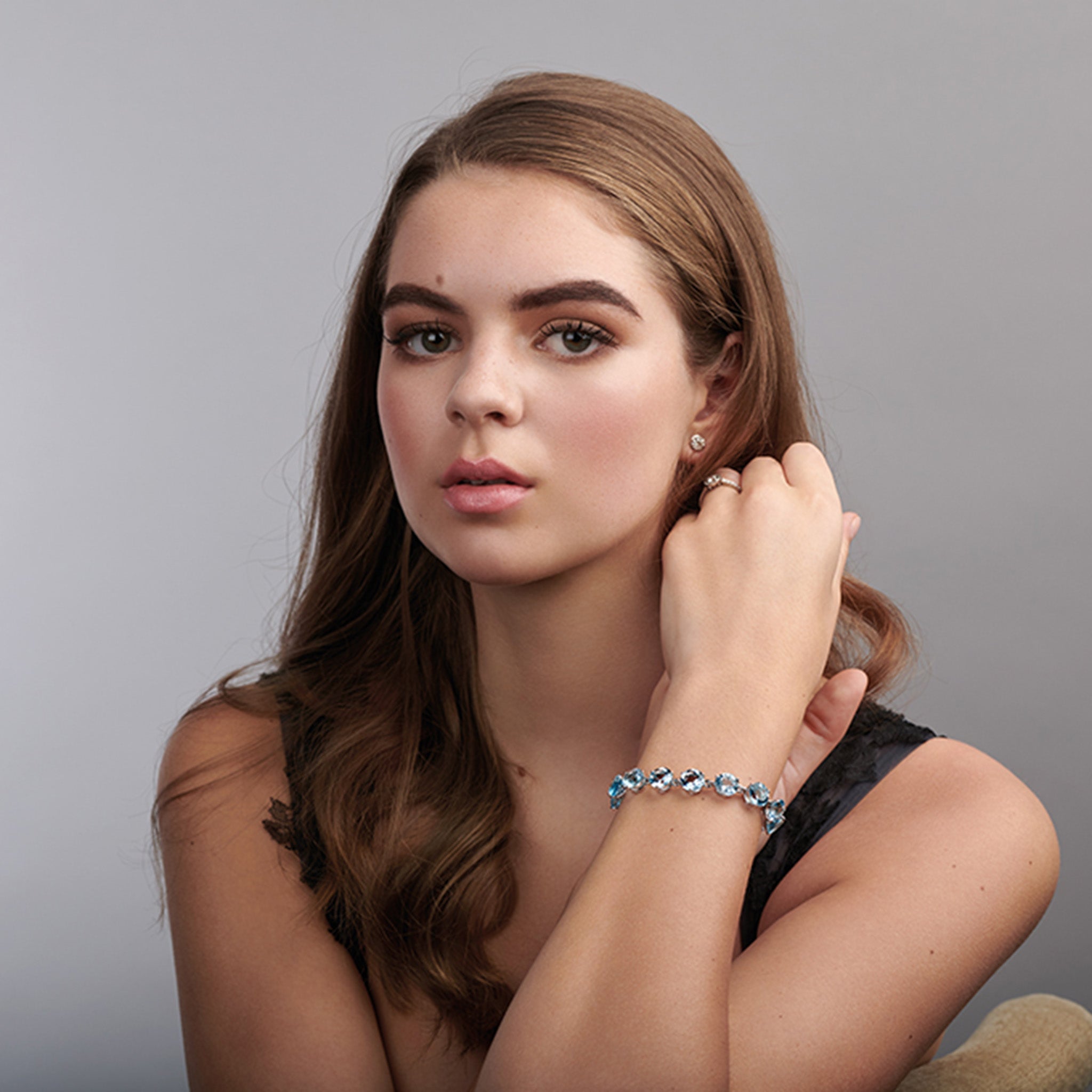 Model wearing a handcrafted yellow gold bracelet featuring circular blue topaz gemstones.