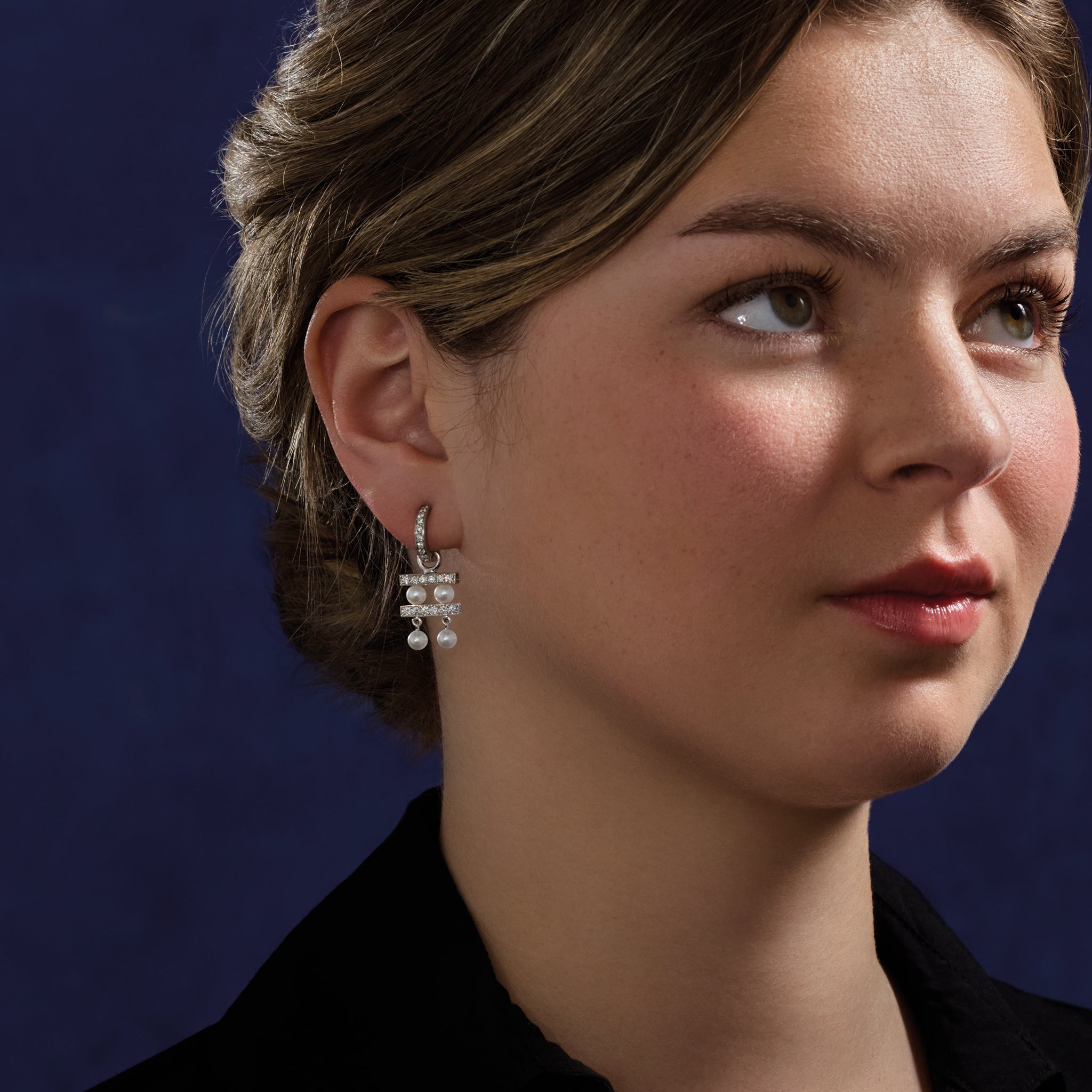 Model wearing handcrafted 18ct white gold earring drops with two tiers of pearls separated by delicate gold lines adorned with diamond pav?.