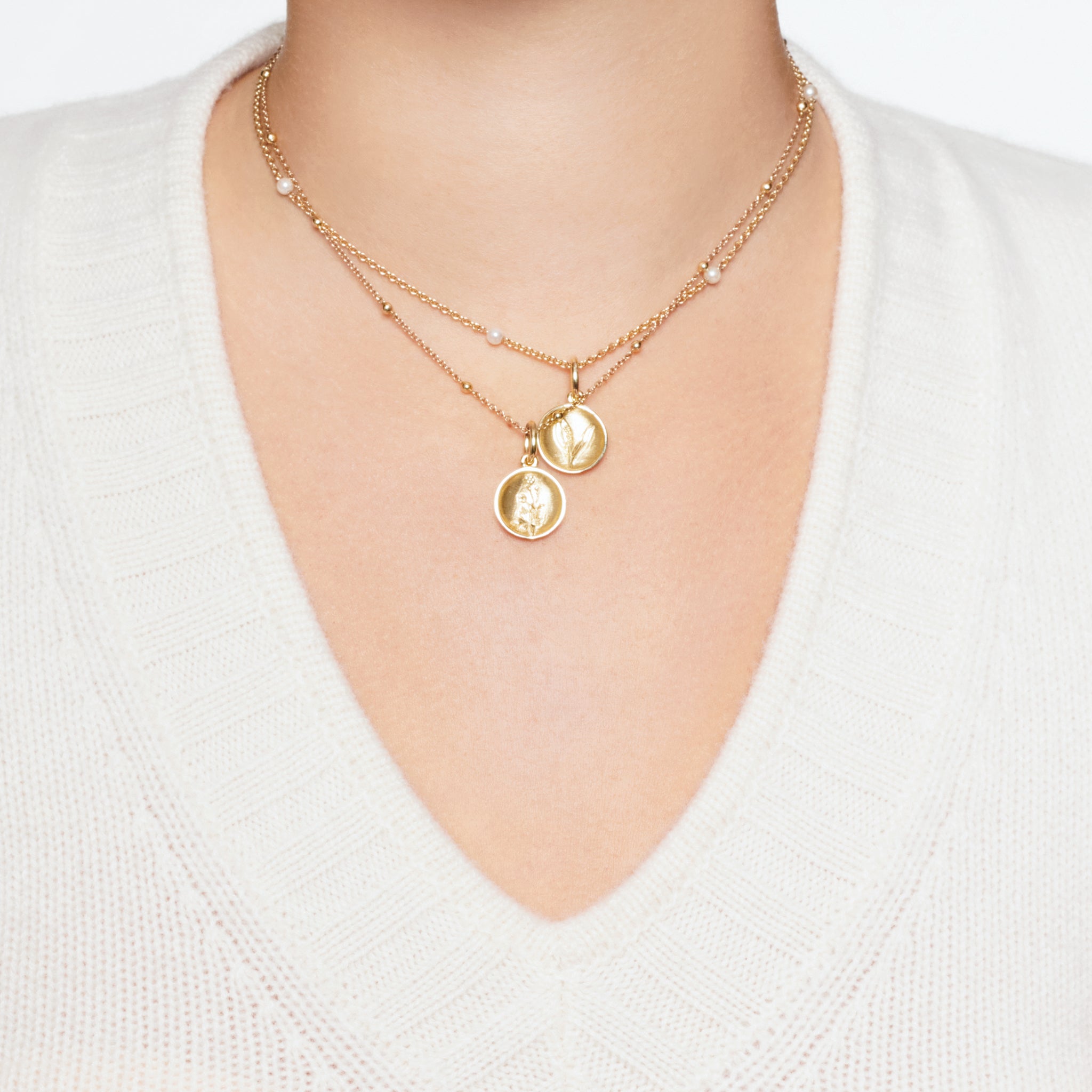 Model wearing a handcrafted round yellow gold necklace pendant 'en relief' with a buttercup flower.