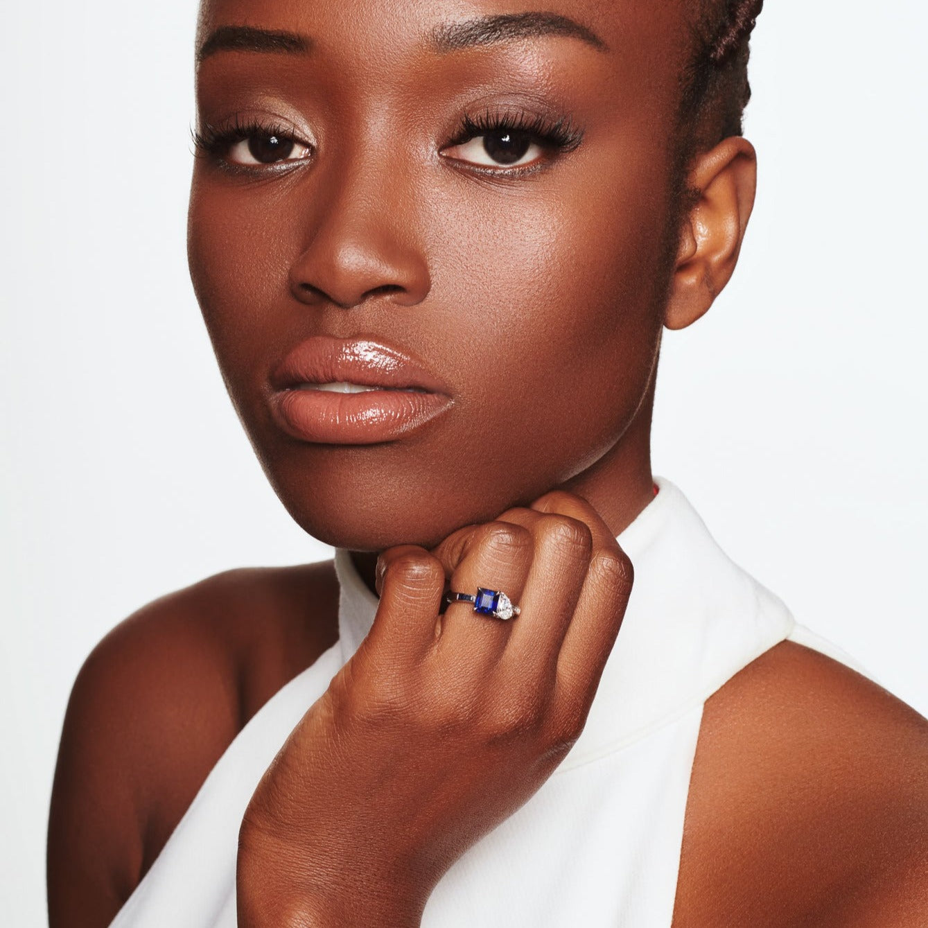 Model wearing a handcrafted platinum engagement ring featuring a square-cut sapphire on the left and a teardrop-shaped diamond on the right.