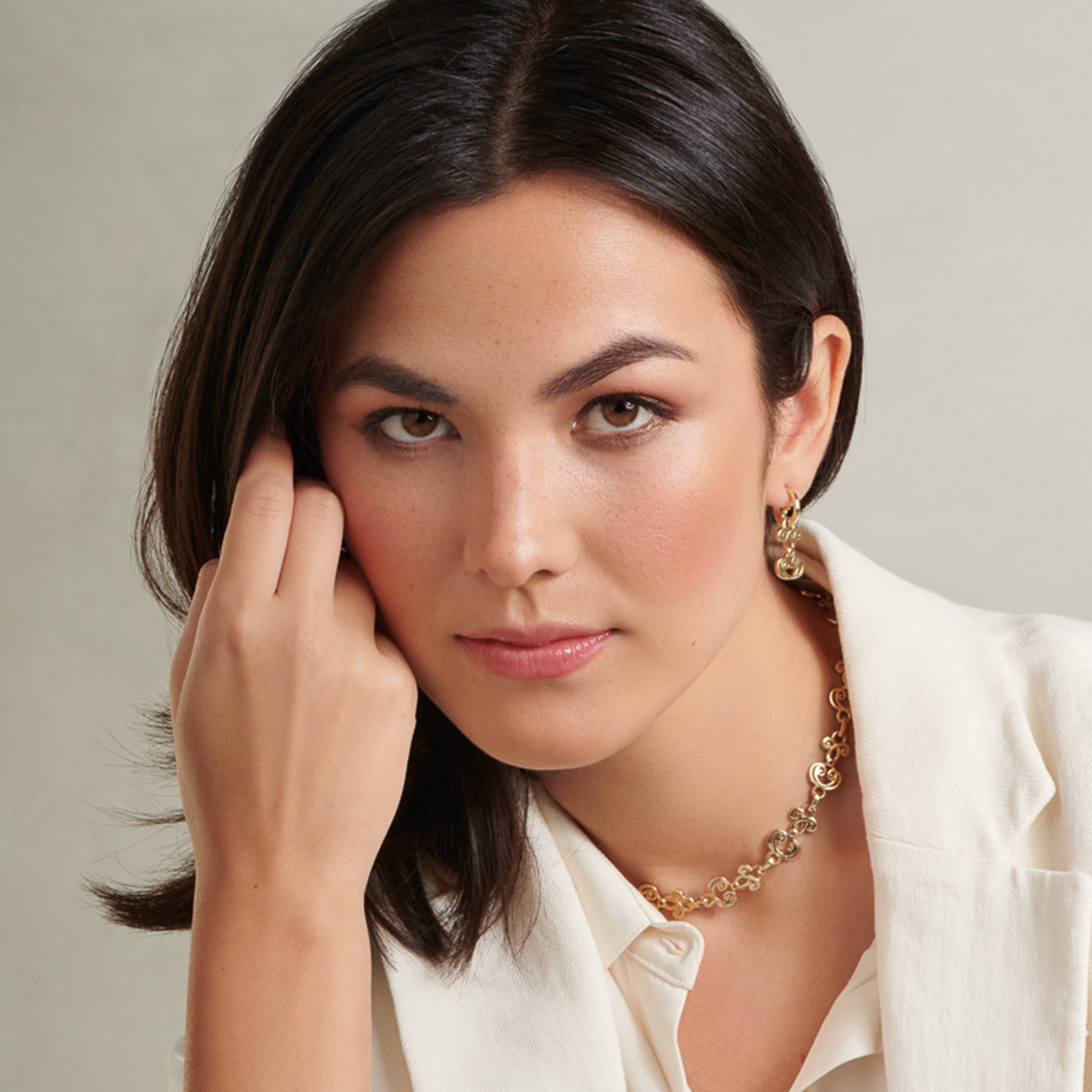 Model wearing handcrafted yellow gold earring drops featuring ironwork motifs from the stables in France.