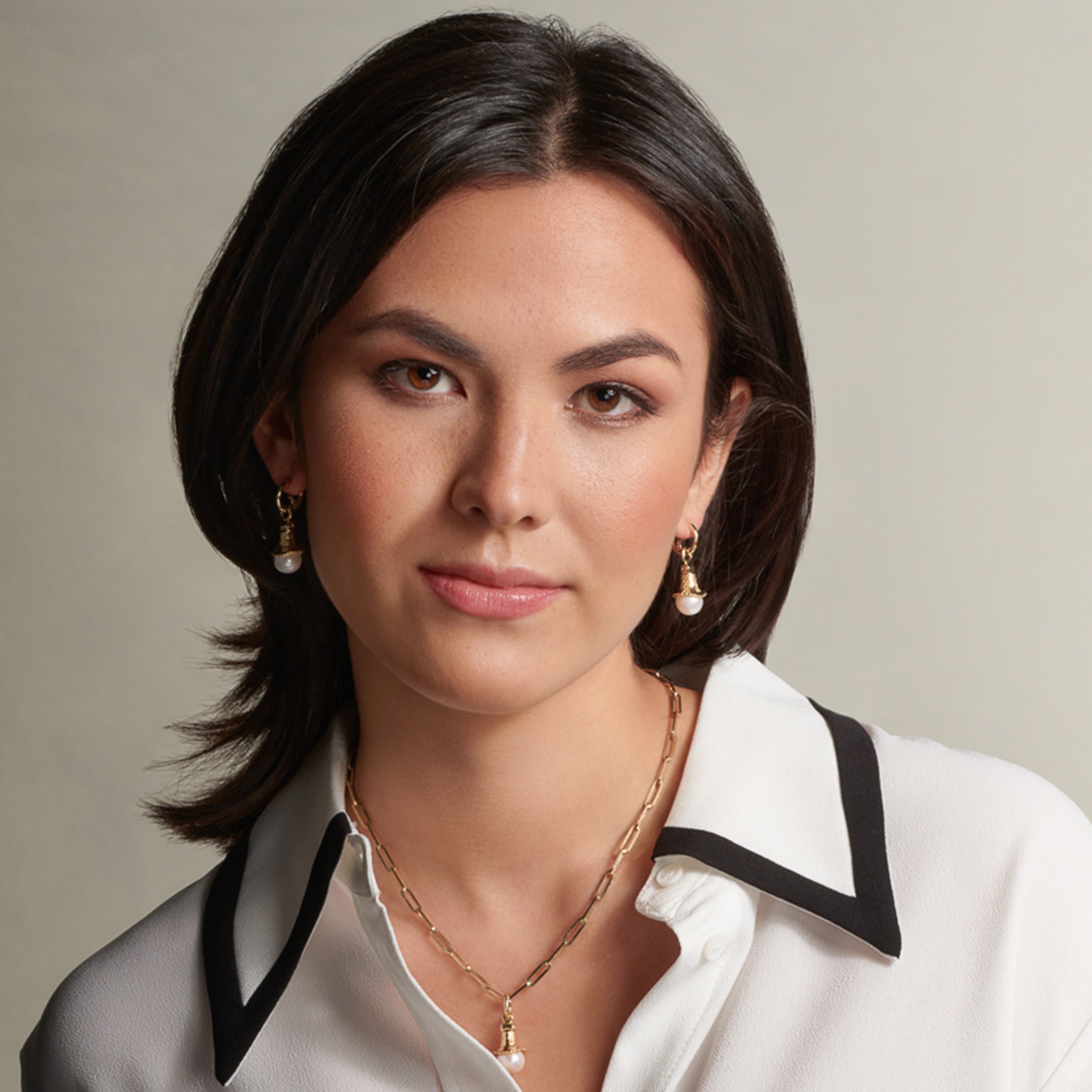 Model wearing handcrafted earring drops in precious metal with a precious stone.