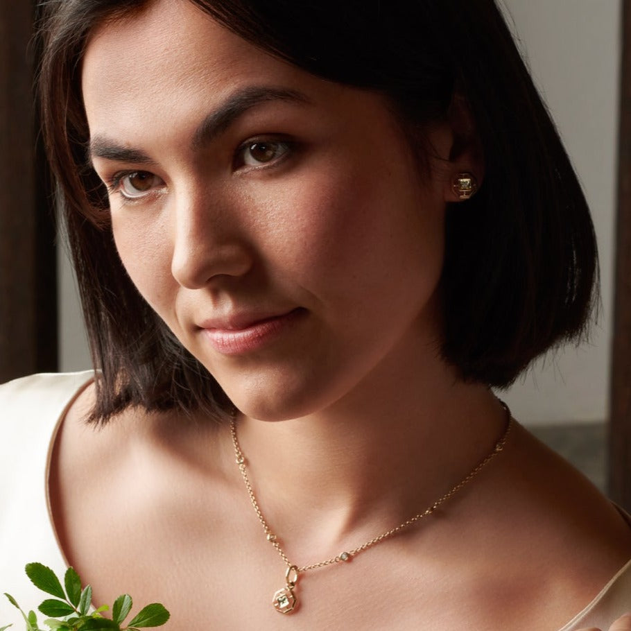 Model wearing a handcrafted necklace pendant featuring an octagonal design with a central precious stone.