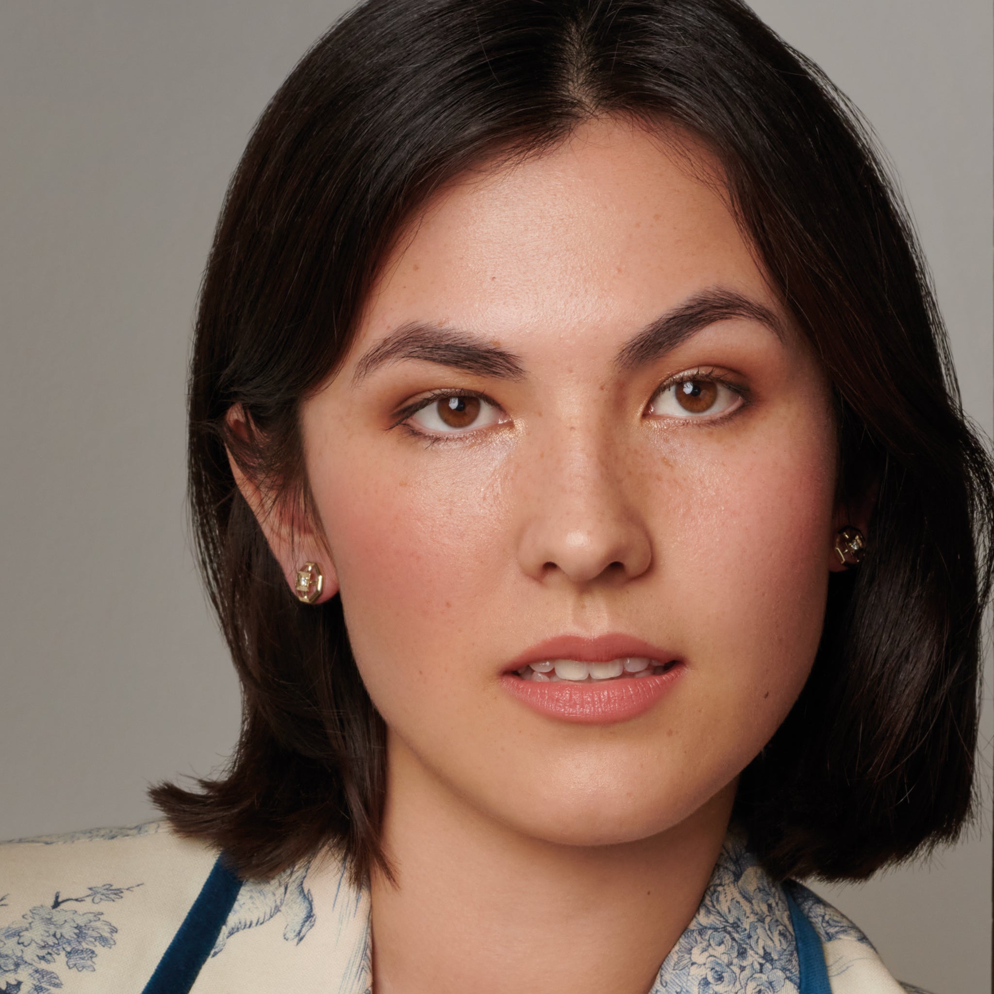 Model wearing handcrafted stud earrings featuring an octagonal design with a central precious stone.