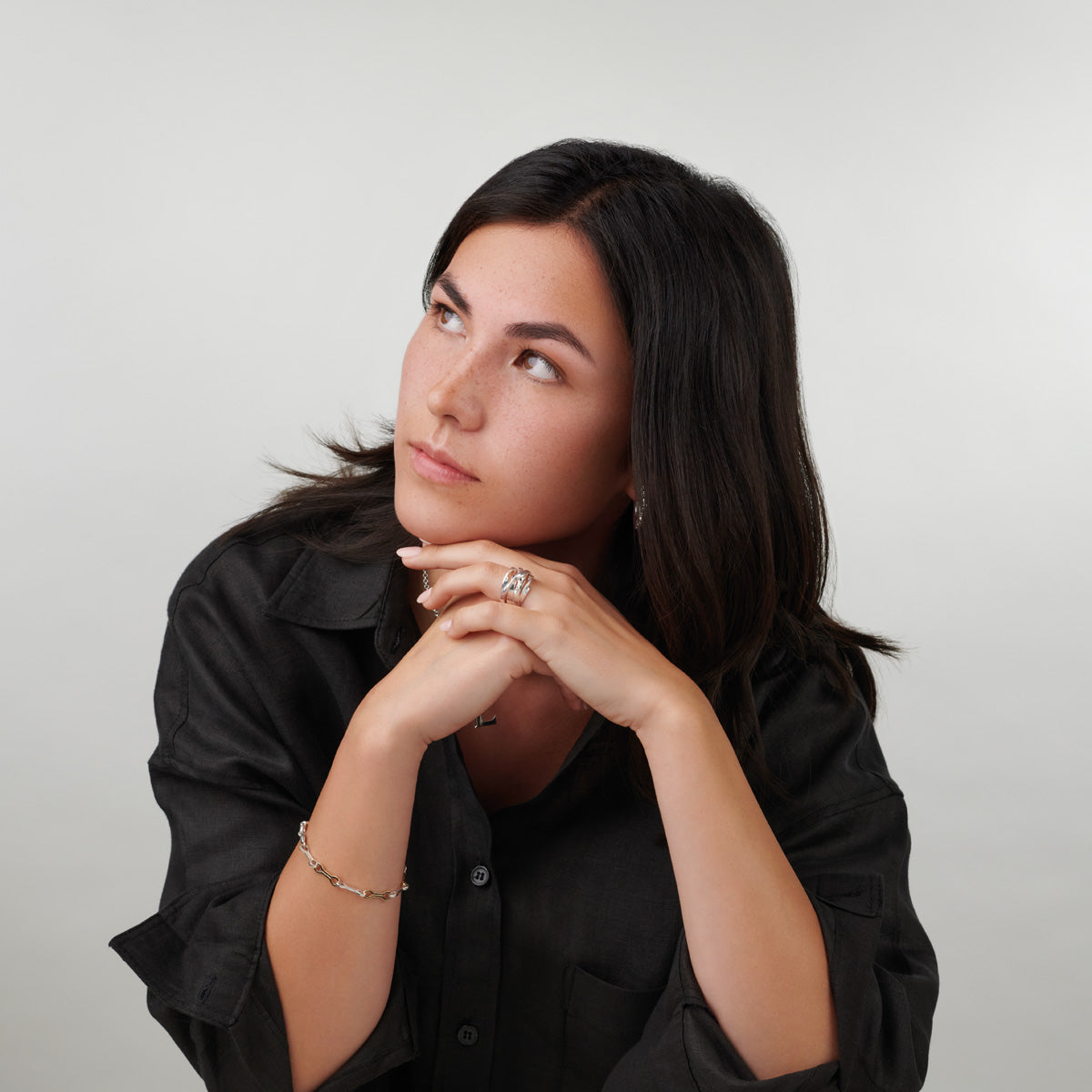 A model wearing a handcrafted mixed metal ring and bracelet in yellow gold and sterling silver.
