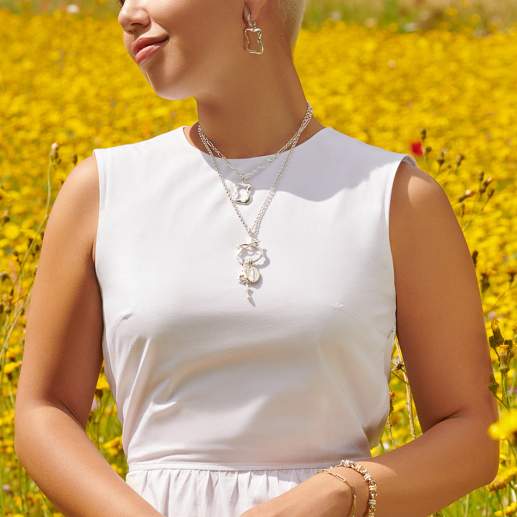 Model wearing a handcrafted sterling silver necklace pendant with three distinct charms elegantly suspended from it.
