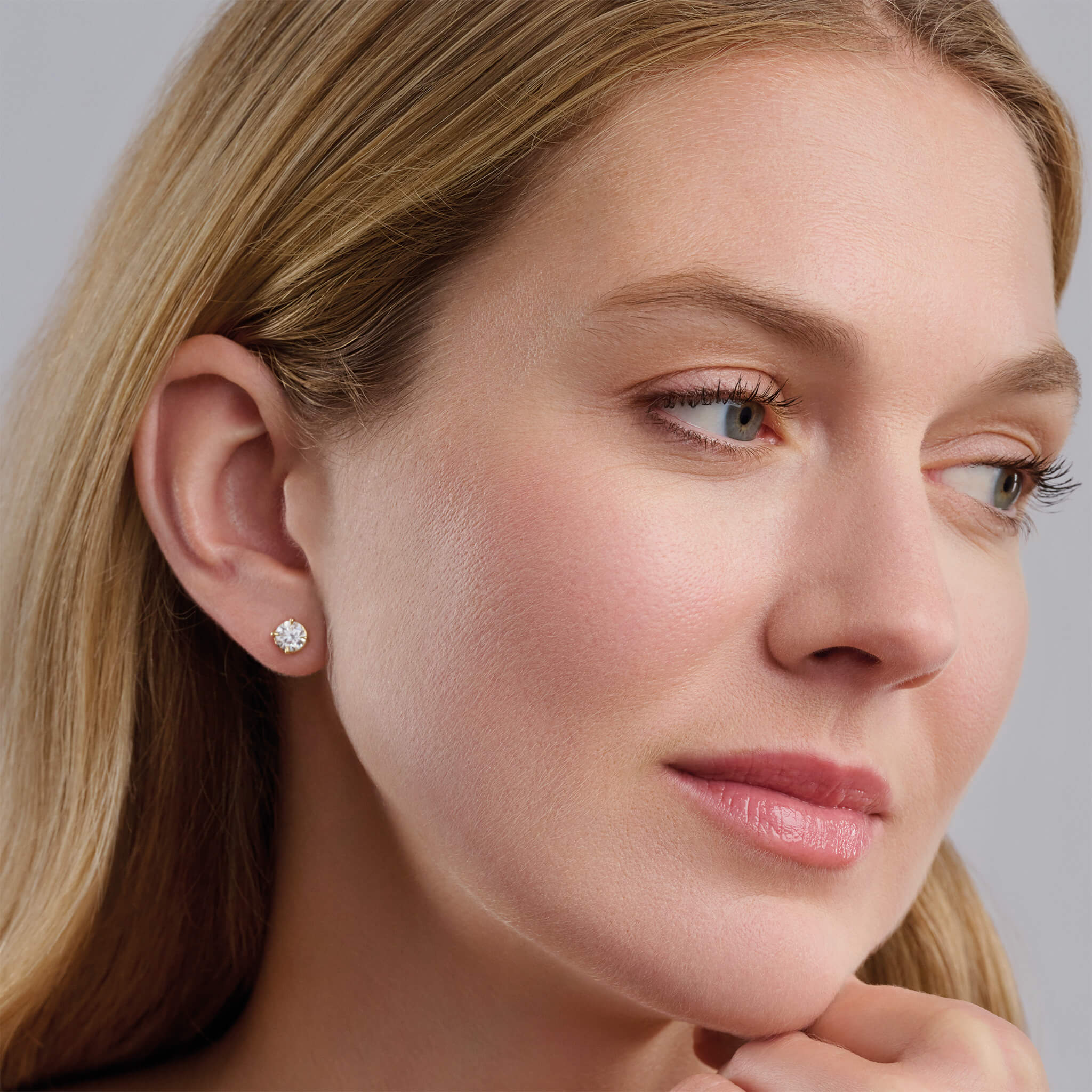 Model wears handcrafted 18ct yellow gold interchangeable stud earrings featuring round diamond, the birthstone of april