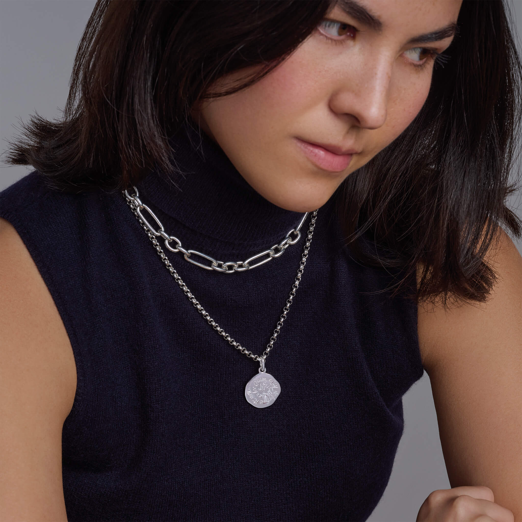 Model wearing handcrafted round silver necklace pendant engraved with the quotes of wisdom.