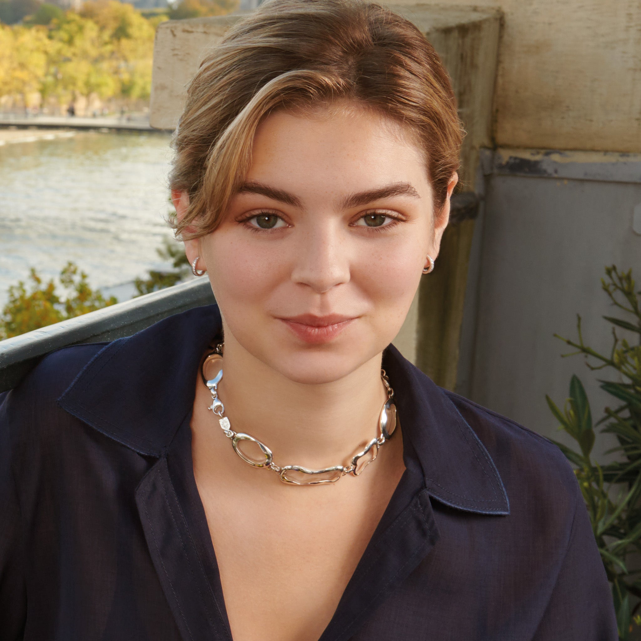 Model wearing a handcrafted sterling silver necklace featuring the outlines of french pastries: ?clair, canel?, pain au chocolat and croissant.