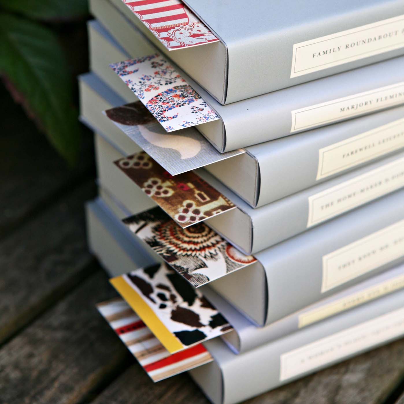 Pile of several Persephone books with their iconic grey cover and colourful bookmarks.