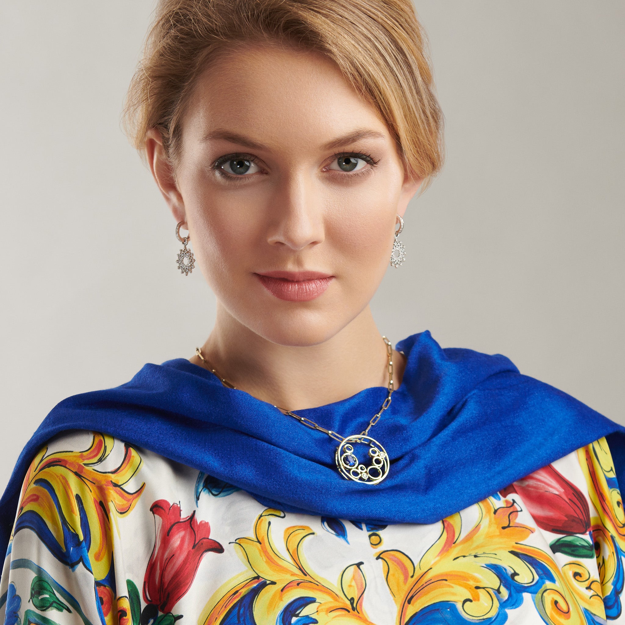 Model wearing a handcrafted yellow gold necklace pendant featuring an open circular design with variously sized cut-out circles.