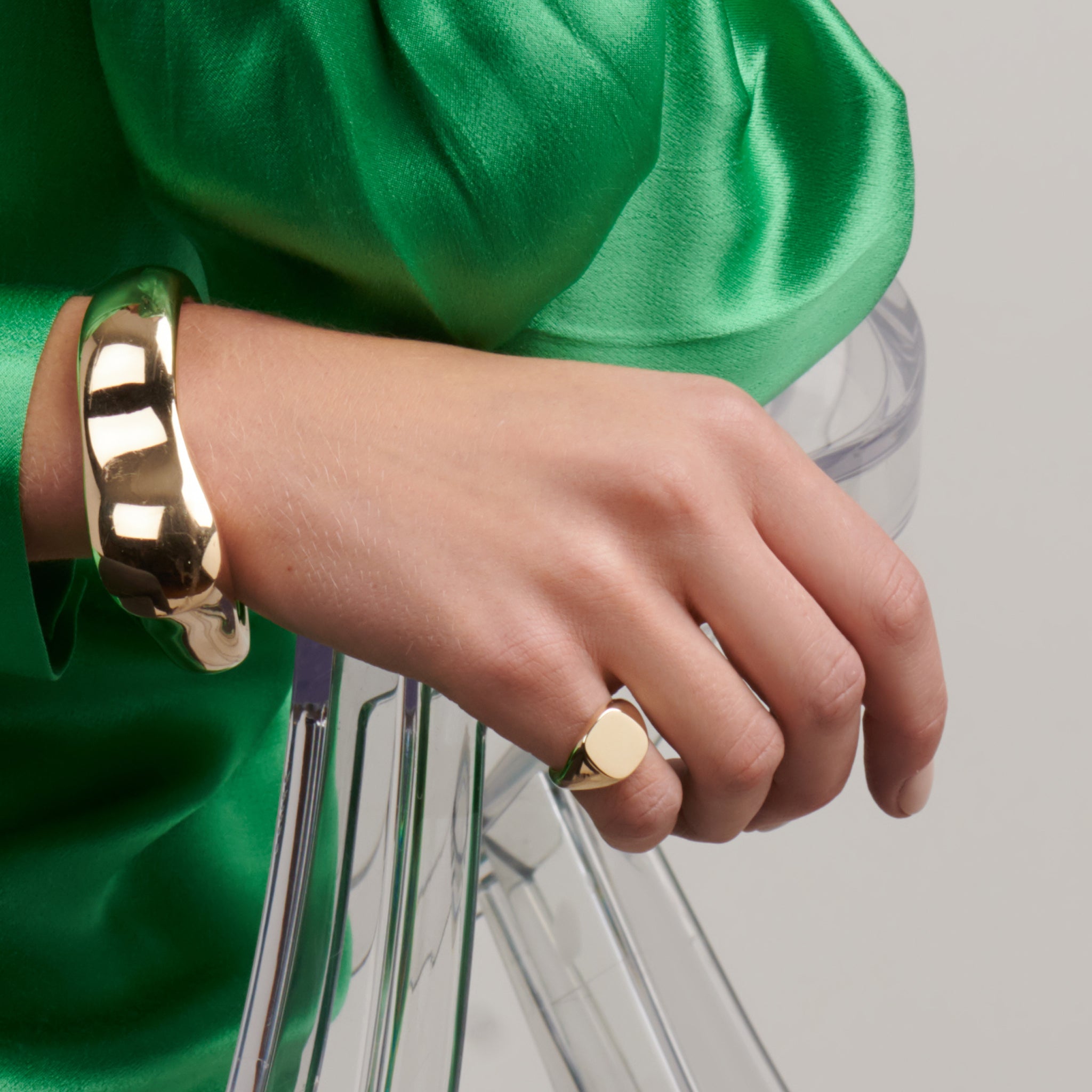 Model wearing a handcrafted yellow gold signet ring featuring a smooth, cushion formed central disc.
