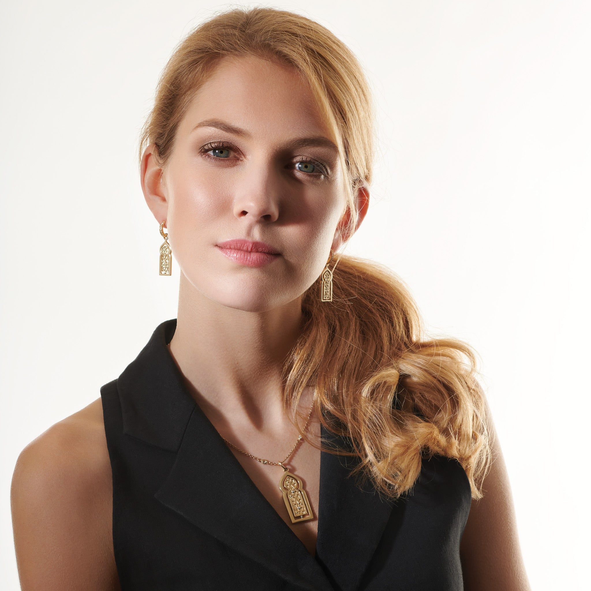 Model wearing a handcrafted yellow gold necklace pendant featuring a narrow door with diamonds.
