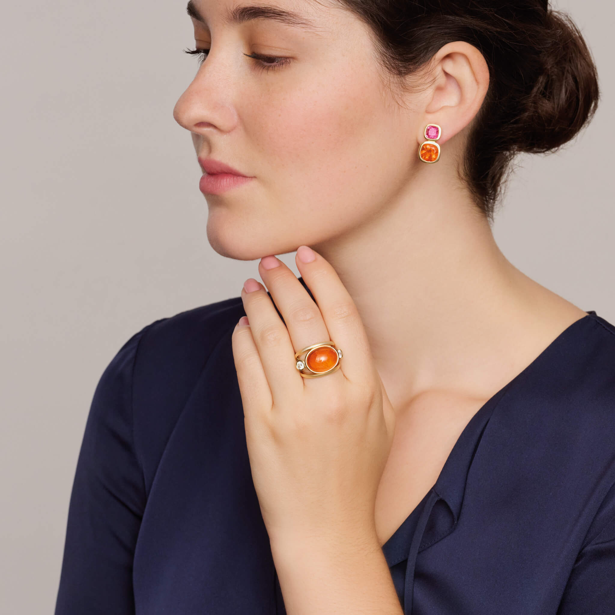 Model wearing handcrafted aeneus ring in 18ct yellow gold with oval cabochon cut mandarin garnet and diamond, inspired by Aeneas of Troy, January birthstone