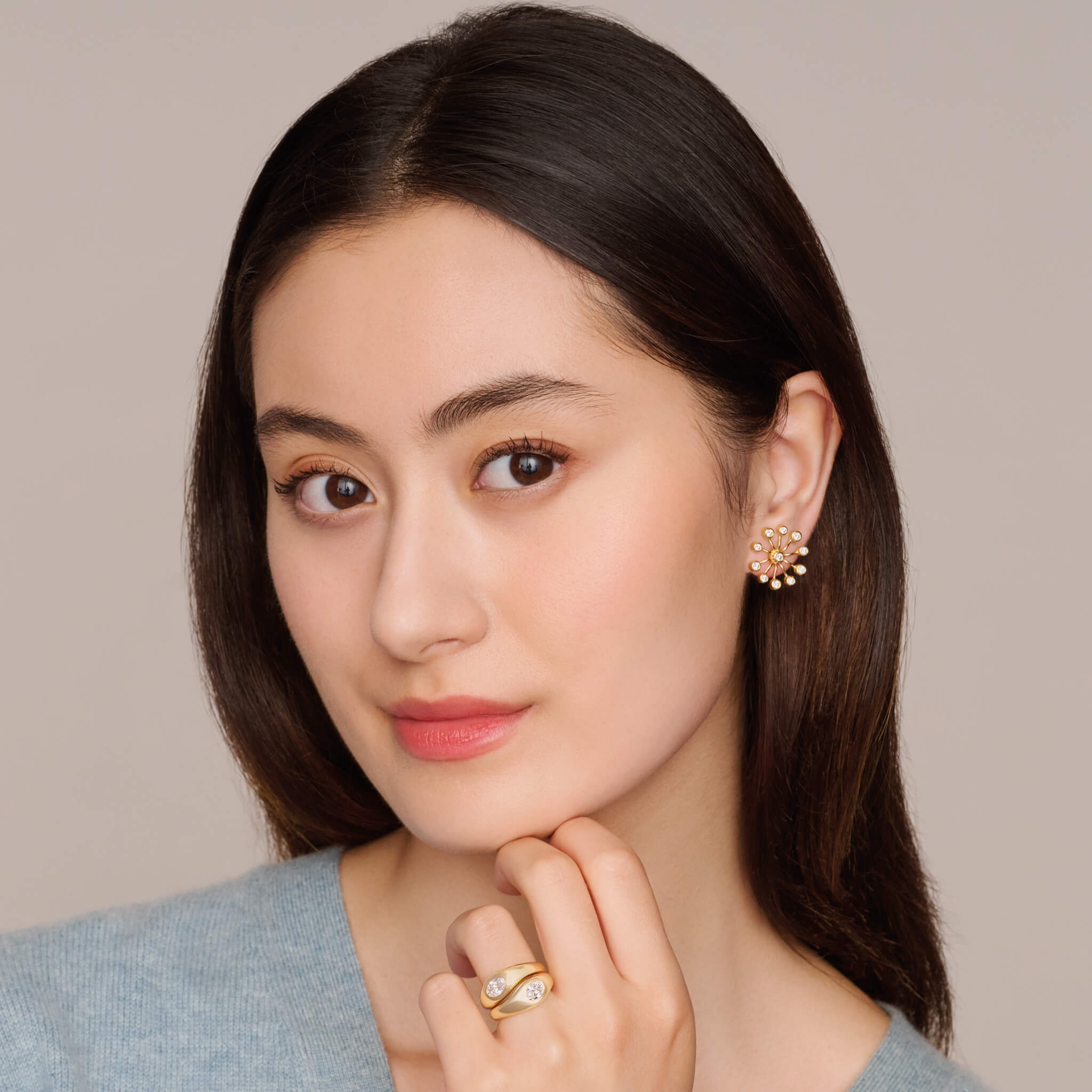 Model wearing handcrafted 18ct yellow gold earrings inspired by the delicate spurs of an astrantia flower, with diamonds set at the tip of each spur.
