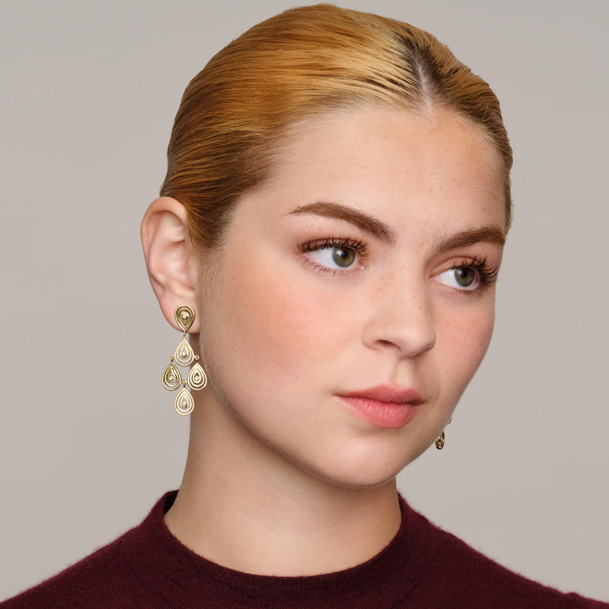 Model wears handcrafted 9ct precious metal earrings with 5 diamonds in a cascading teardrop outline.