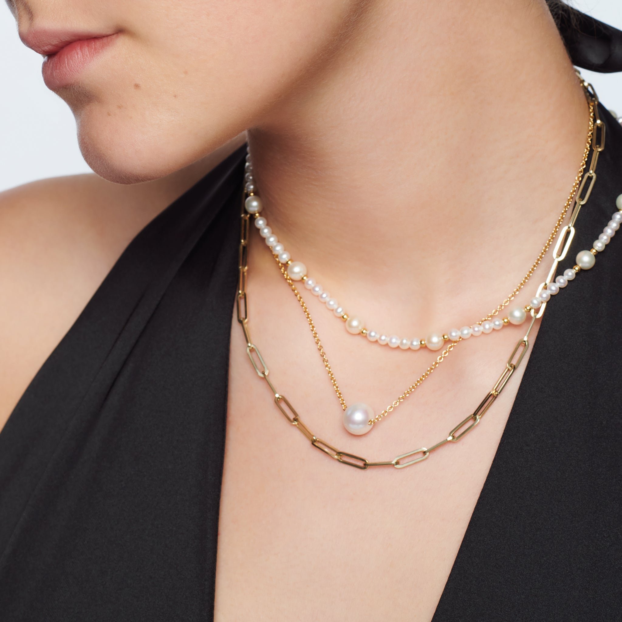 Model wearing a handcrafted necklace in precious metal featuring a round precious stone.