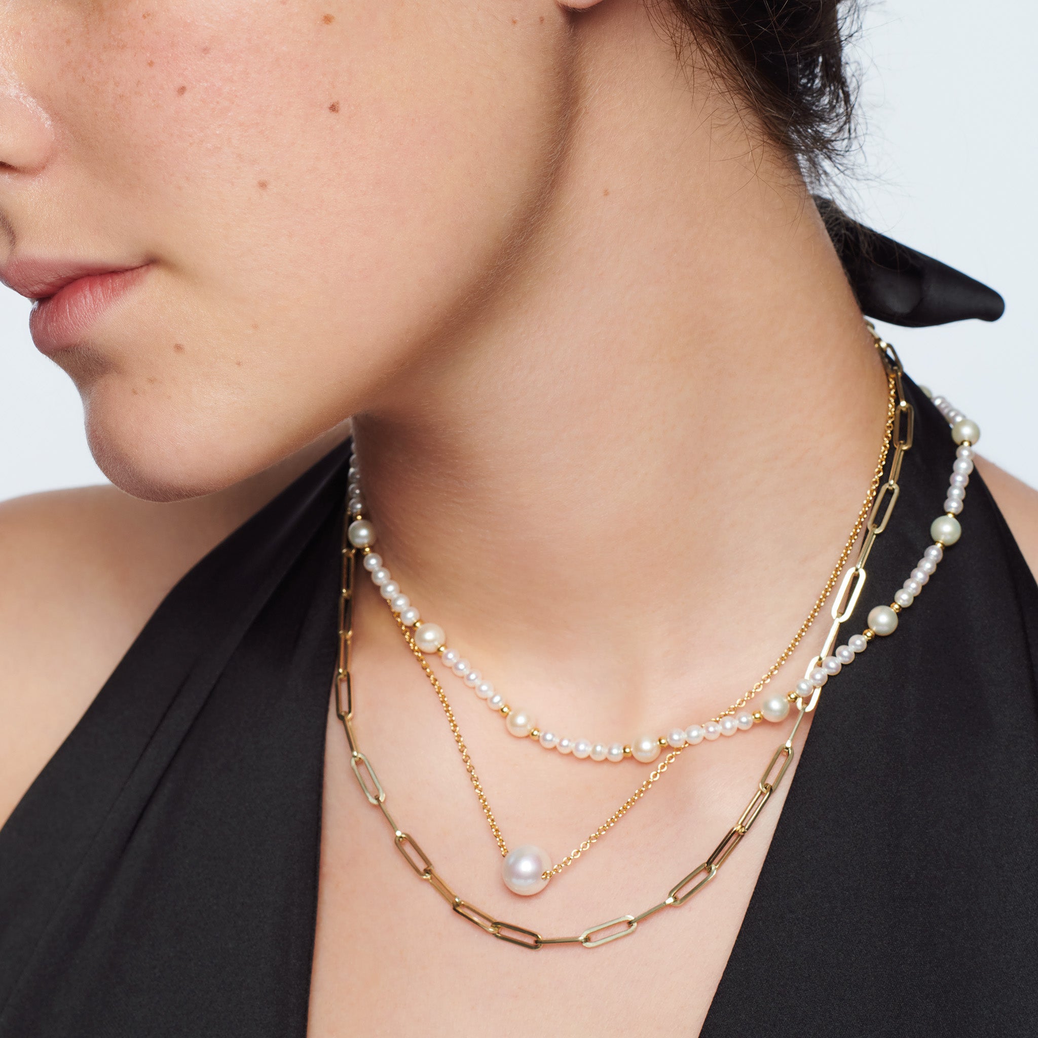 Model wearing a handcrafted yellow gold necklace with small pearls.